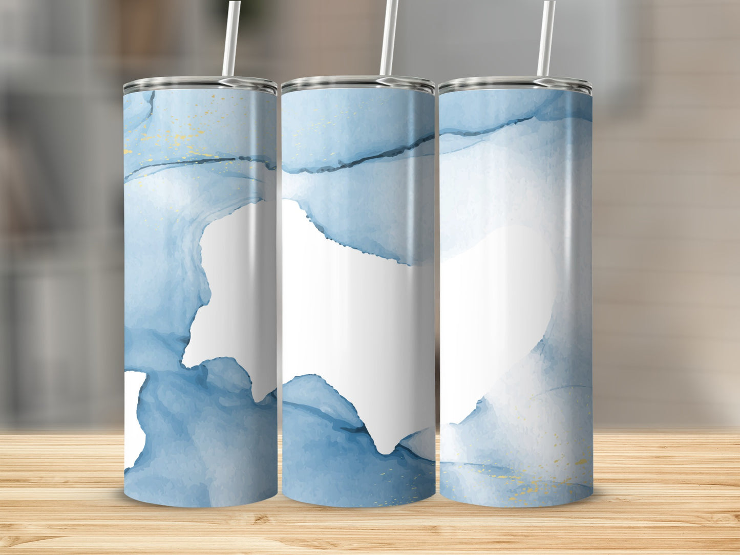 Three tumblers with blue watercolor and gold accents, on a wooden surface.
