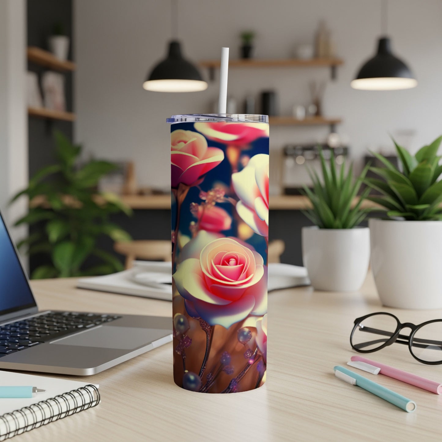 Pink and white roses adorn a tumbler with a straw, resting on a desk.