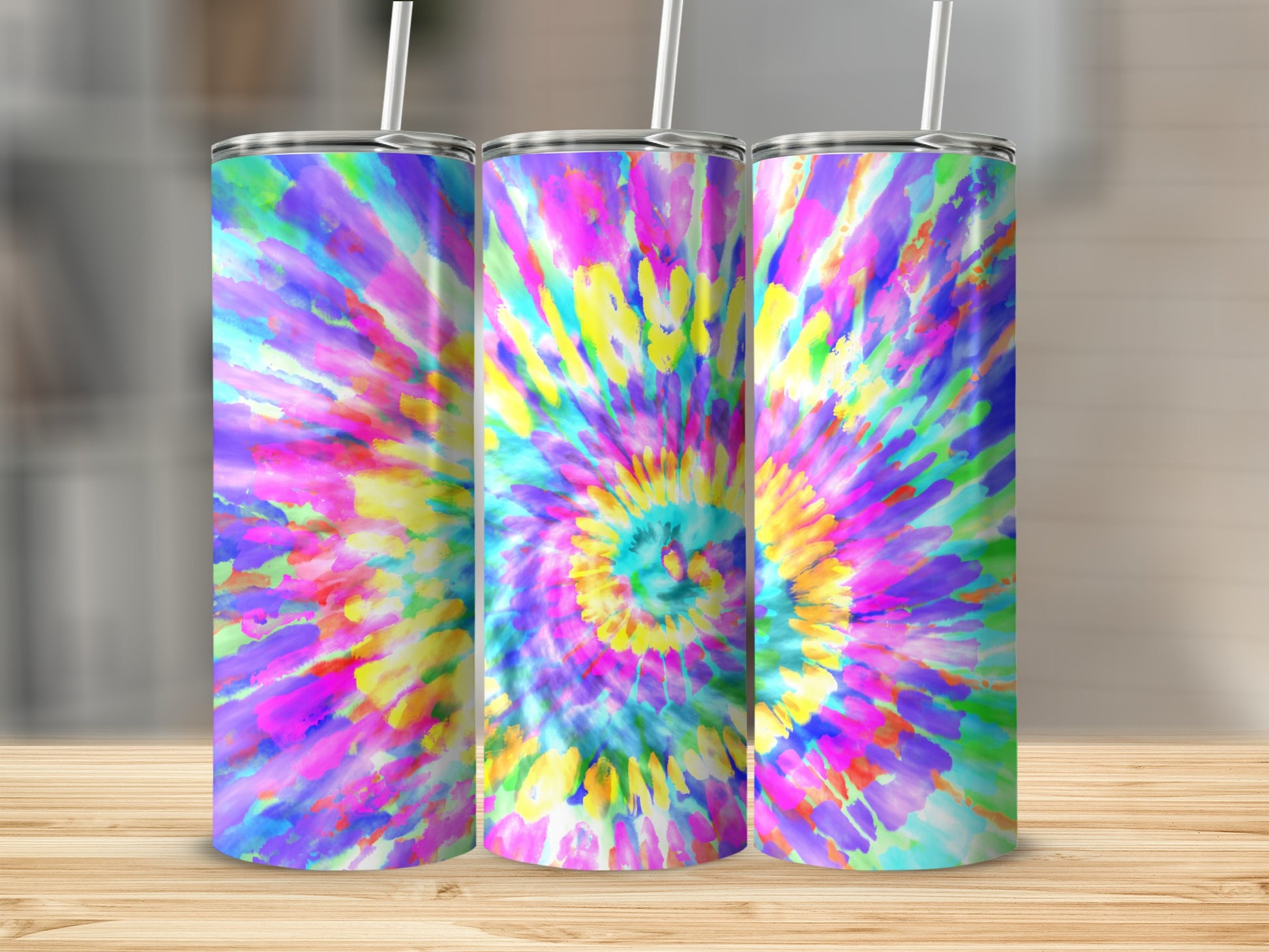 Three tumblers with colorful tie-dye patterns sit on a wooden surface.