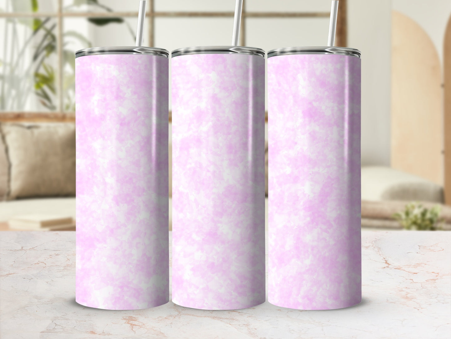 Three pink marbled tumblers with straws stand on a marble countertop.