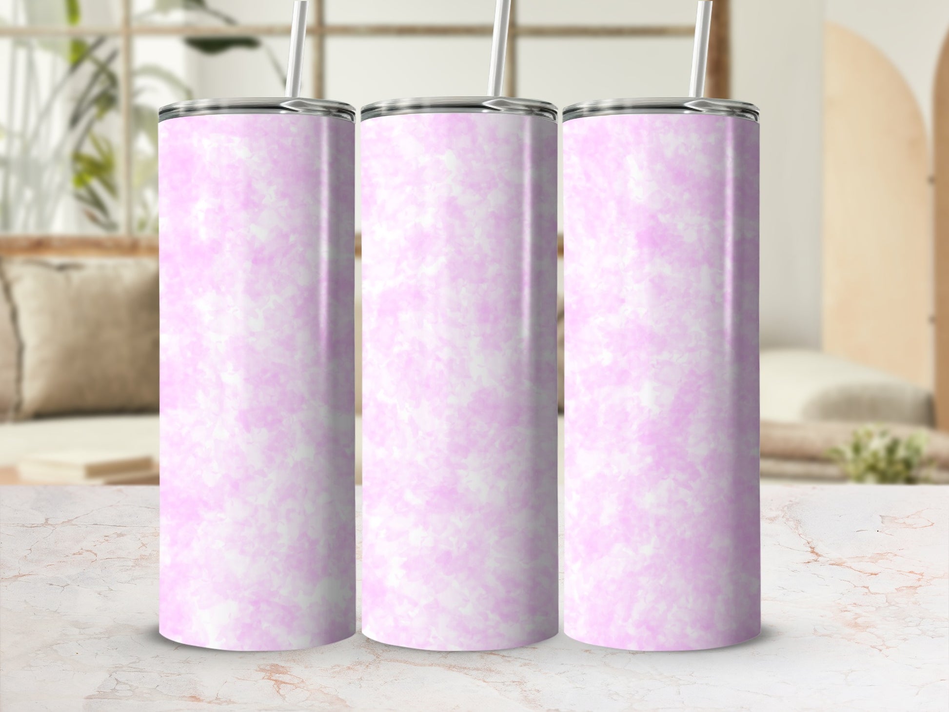 Three pink marbled tumblers with straws stand on a marble countertop.