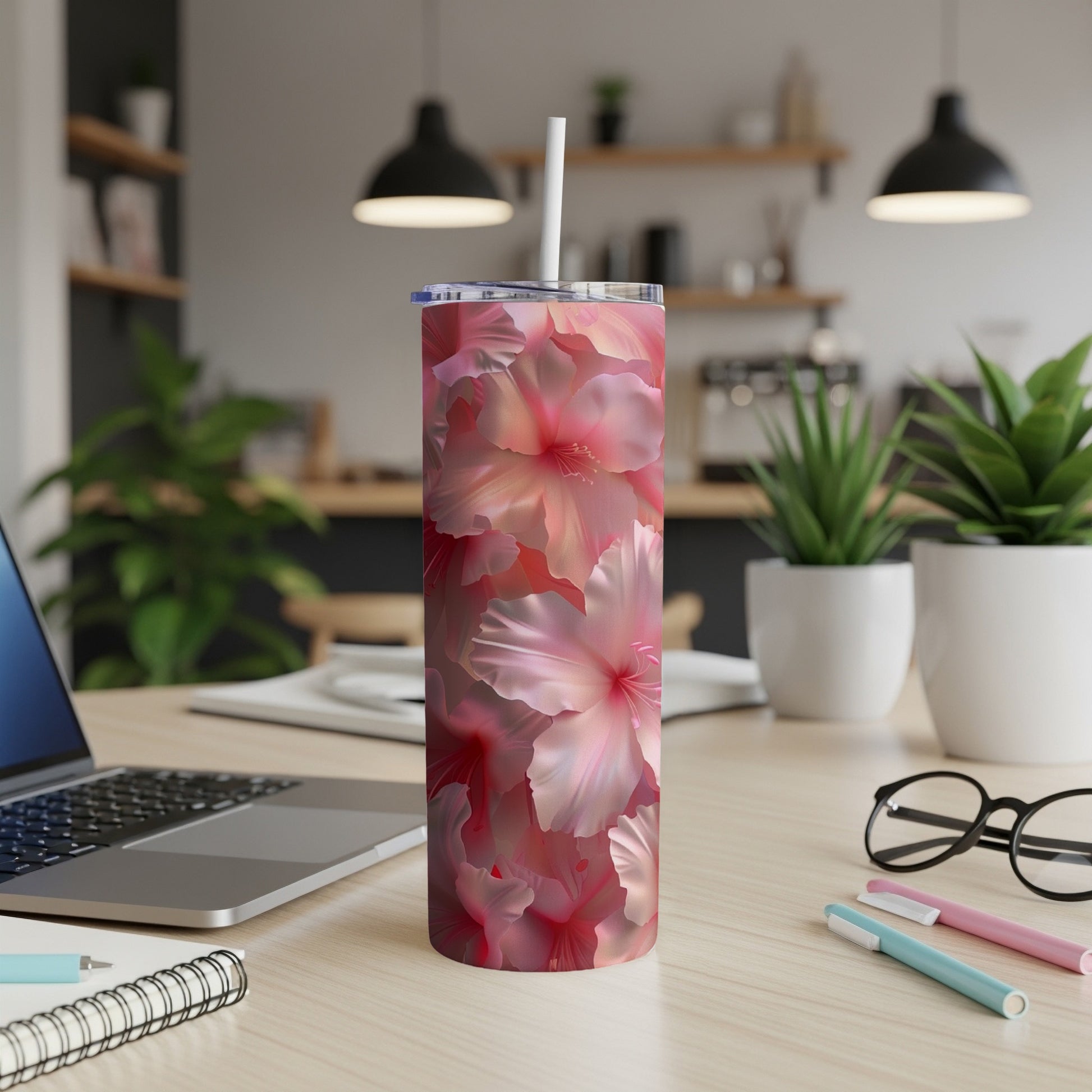 Pink hibiscus floral print tumbler with white straw on desk.