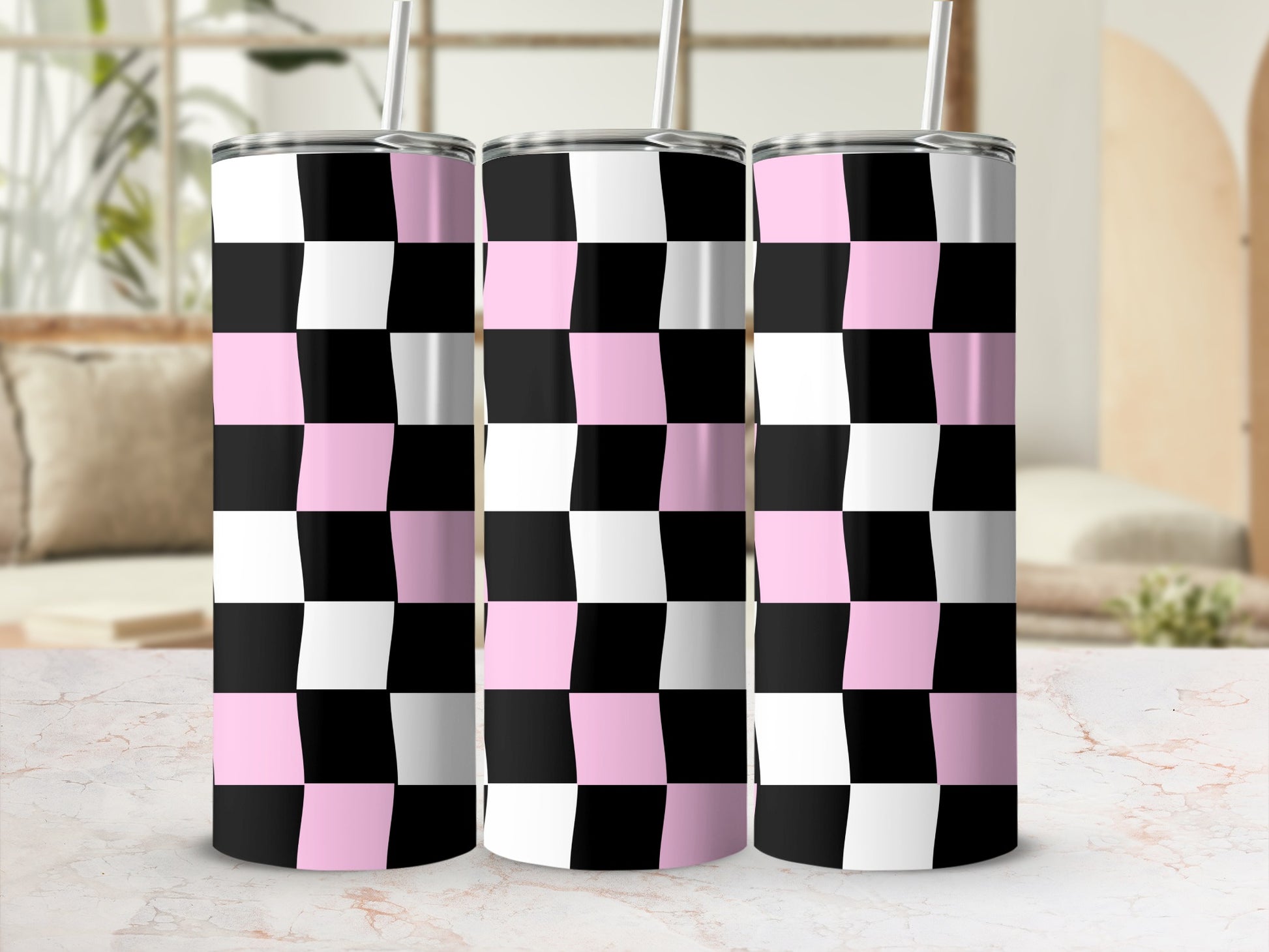Pink, black, and white checkered tumblers with straws on a marble surface.