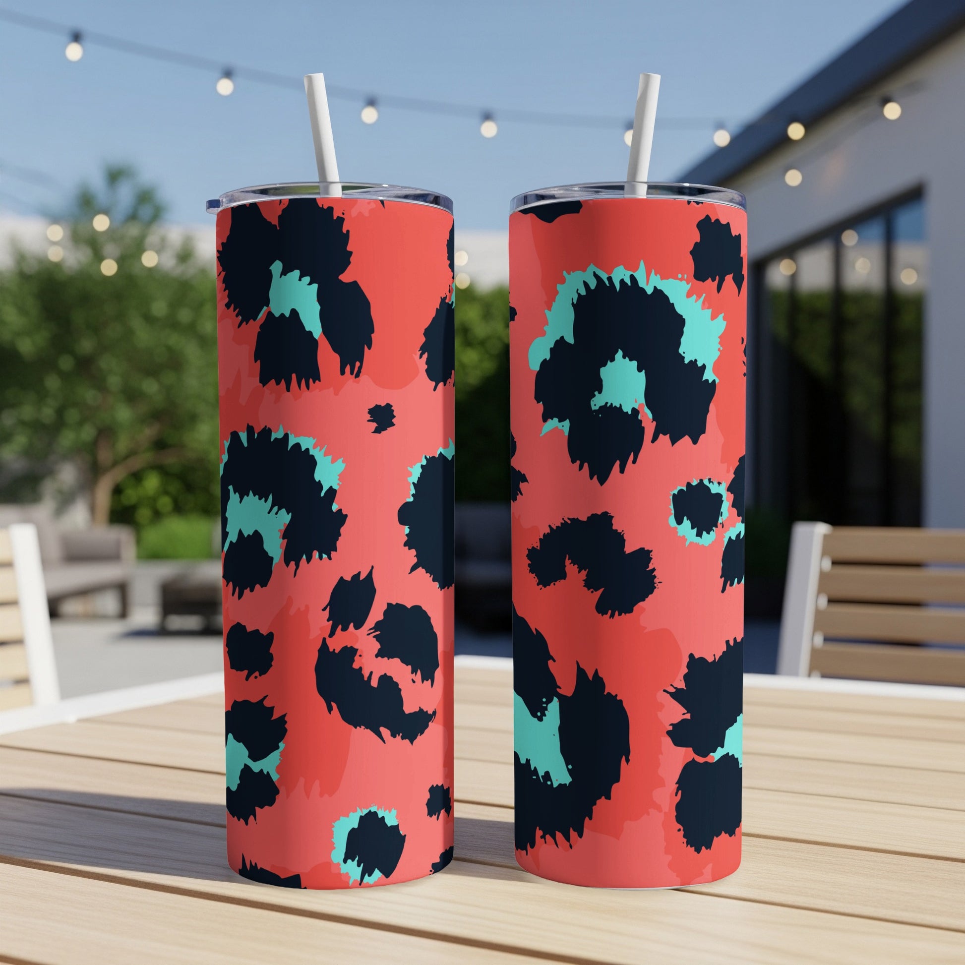 Two coral tumblers with black and teal leopard print and white straws.