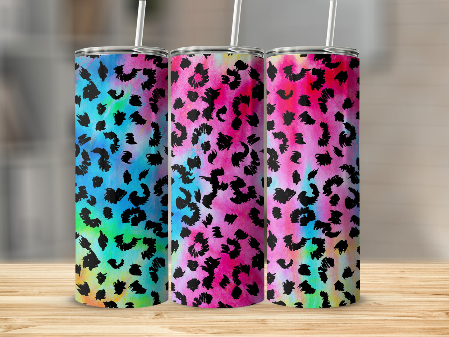 Three tumblers with colorful leopard print designs and white straws.