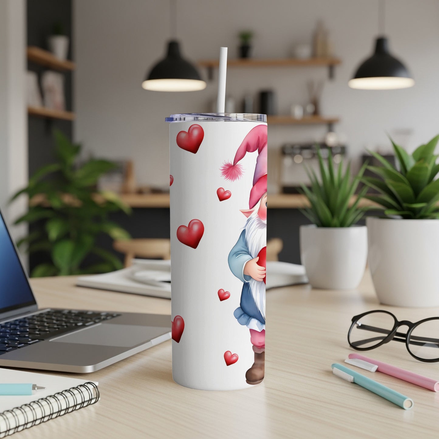 White tumbler with gnome and red hearts pattern, on a desk.