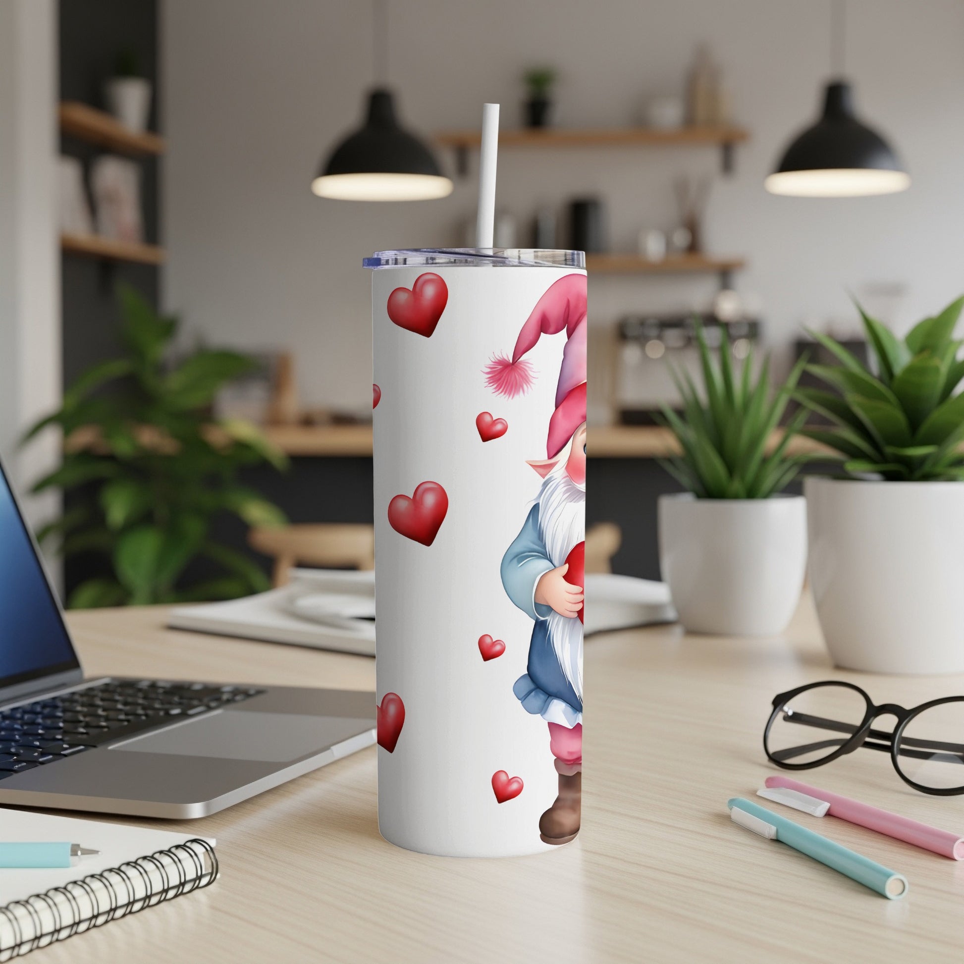 White tumbler with gnome and red hearts pattern, on a desk.