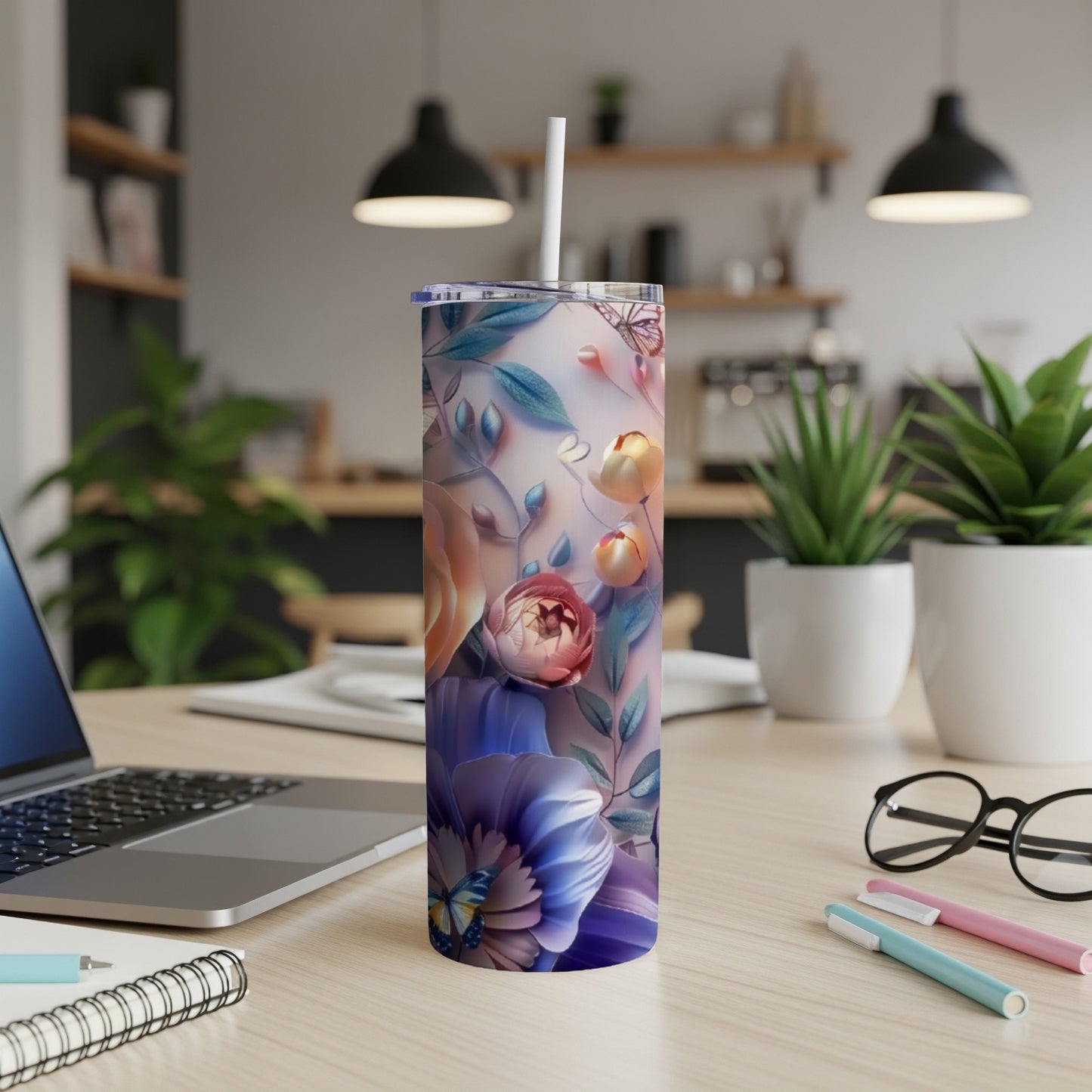 Floral tumbler with butterflies on a desk with laptop and pens.