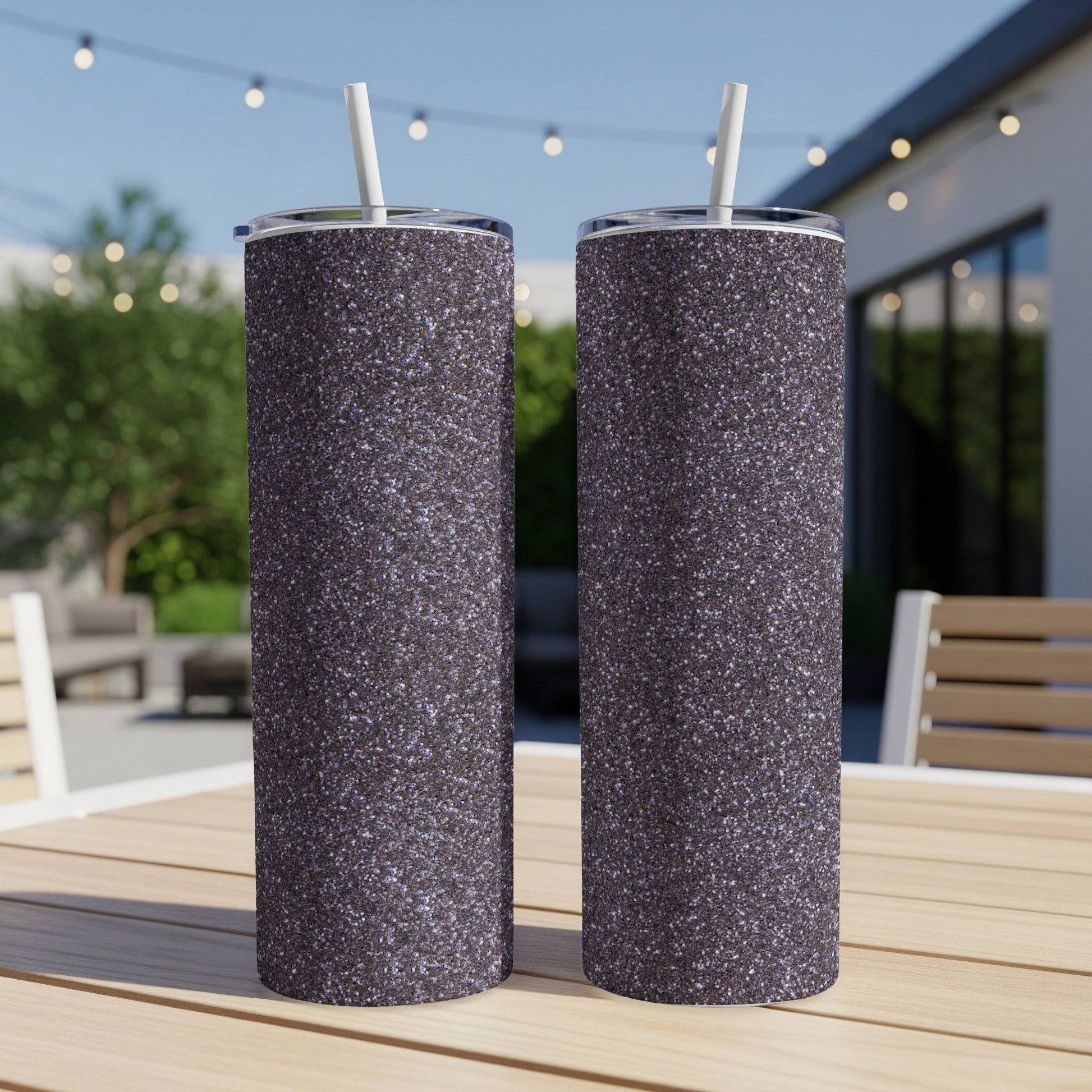 Two glittery tumblers with white straws stand on a wooden table.