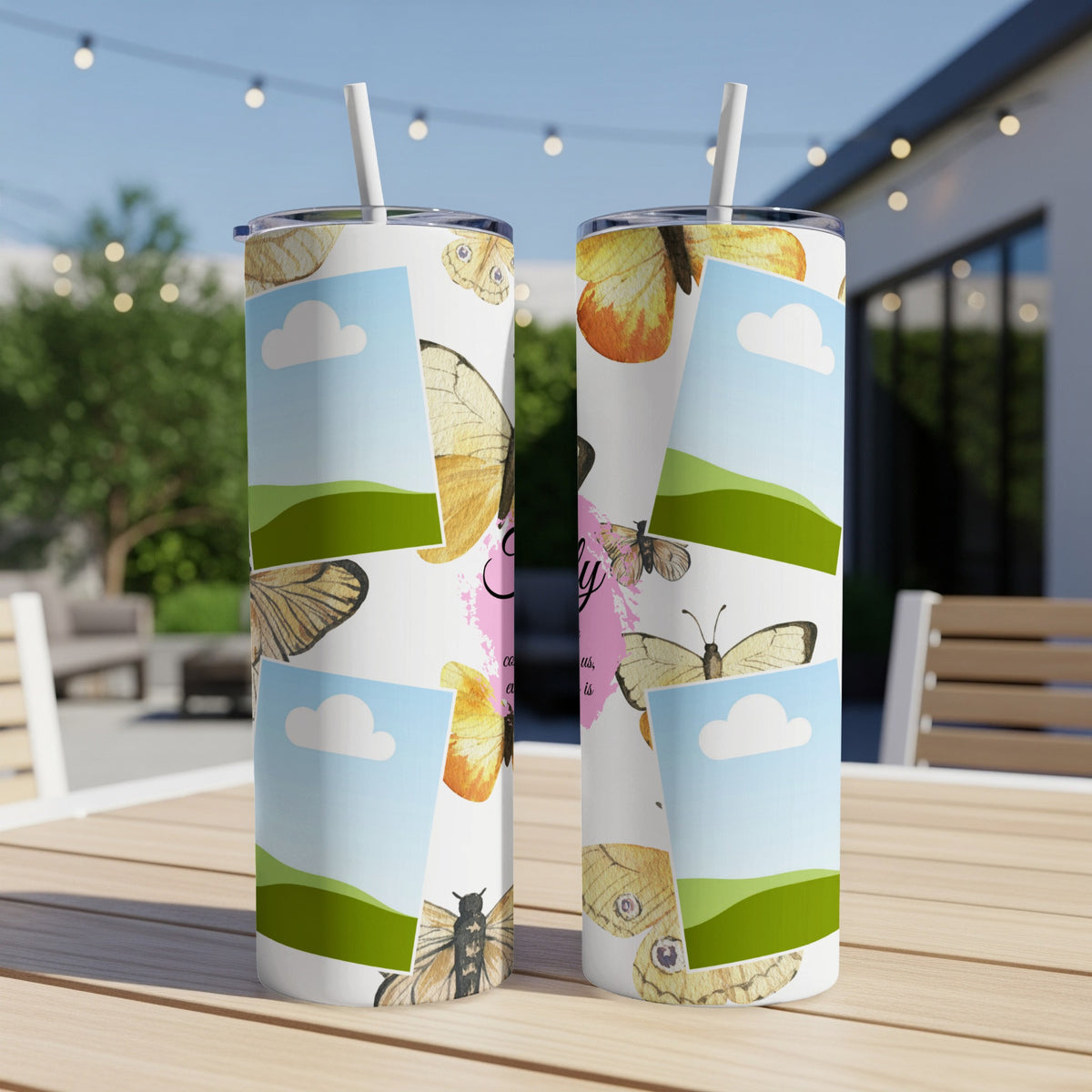 Two tumblers with butterfly and cloud designs displayed on a wooden table outdoors.
