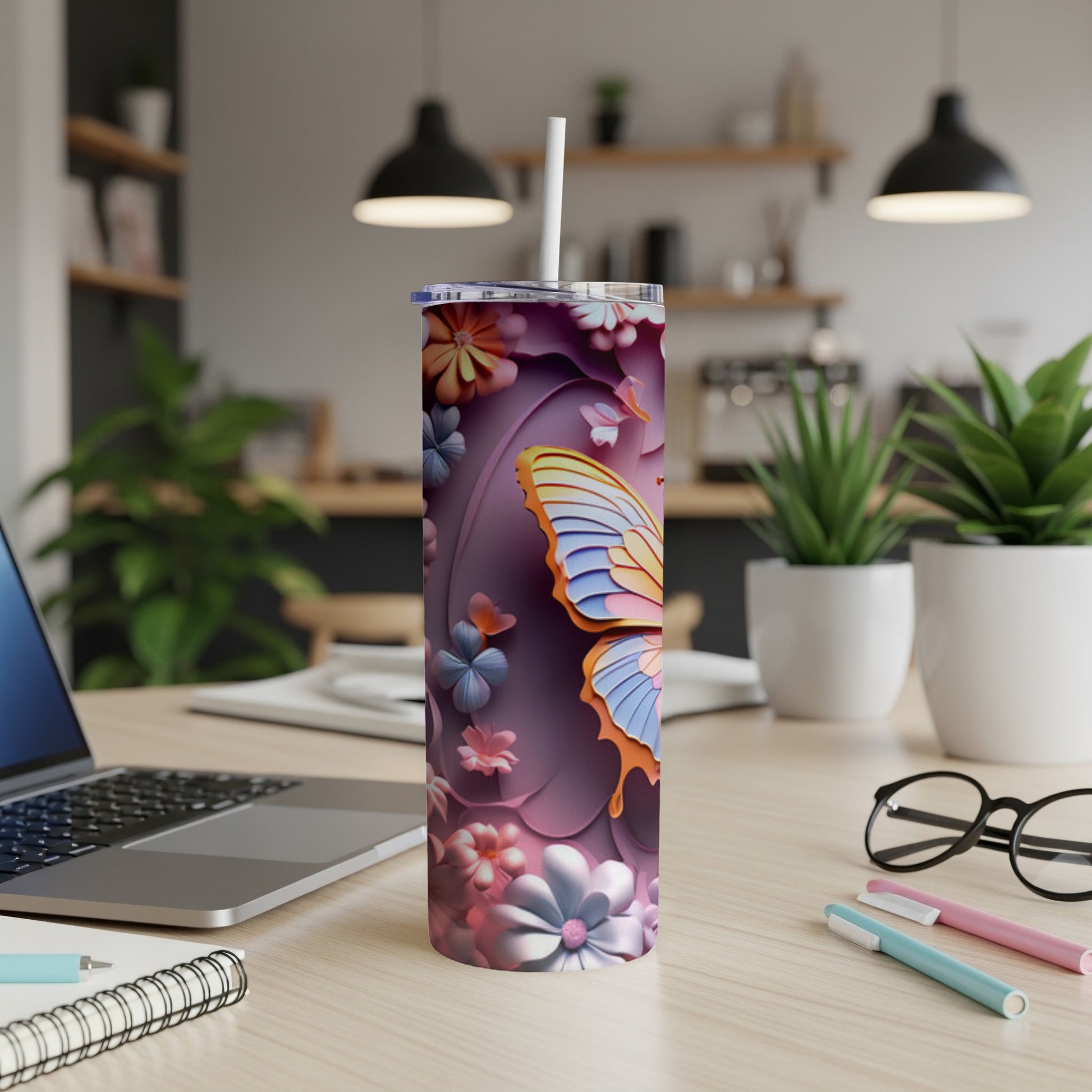 Tumbler with butterfly and floral design on a desk.