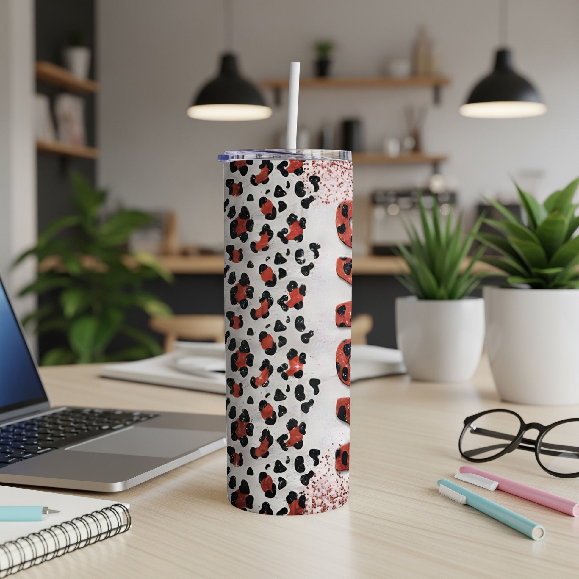 White leopard print tumbler with "mama" text, laptop, and pens on desk.