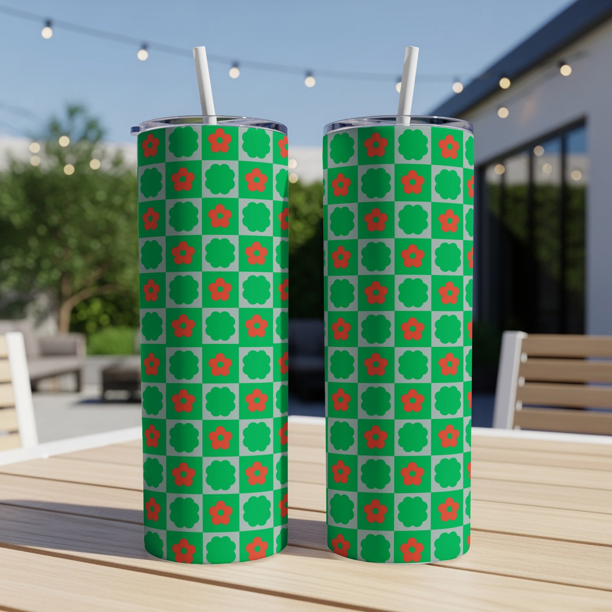 Two green tumblers with a red floral checkered pattern on a wooden table.