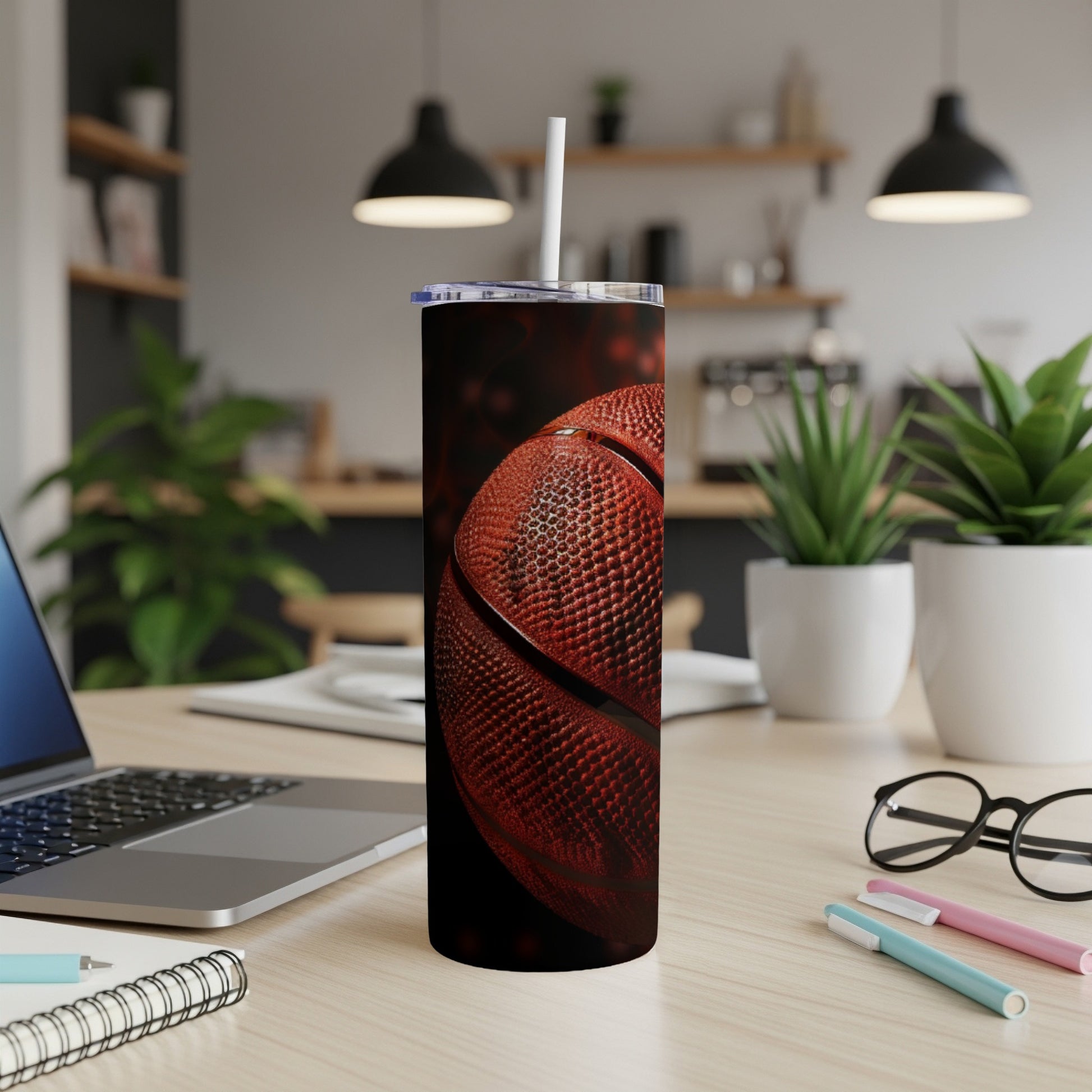 Basketball tumbler with straw on a desk next to a laptop.