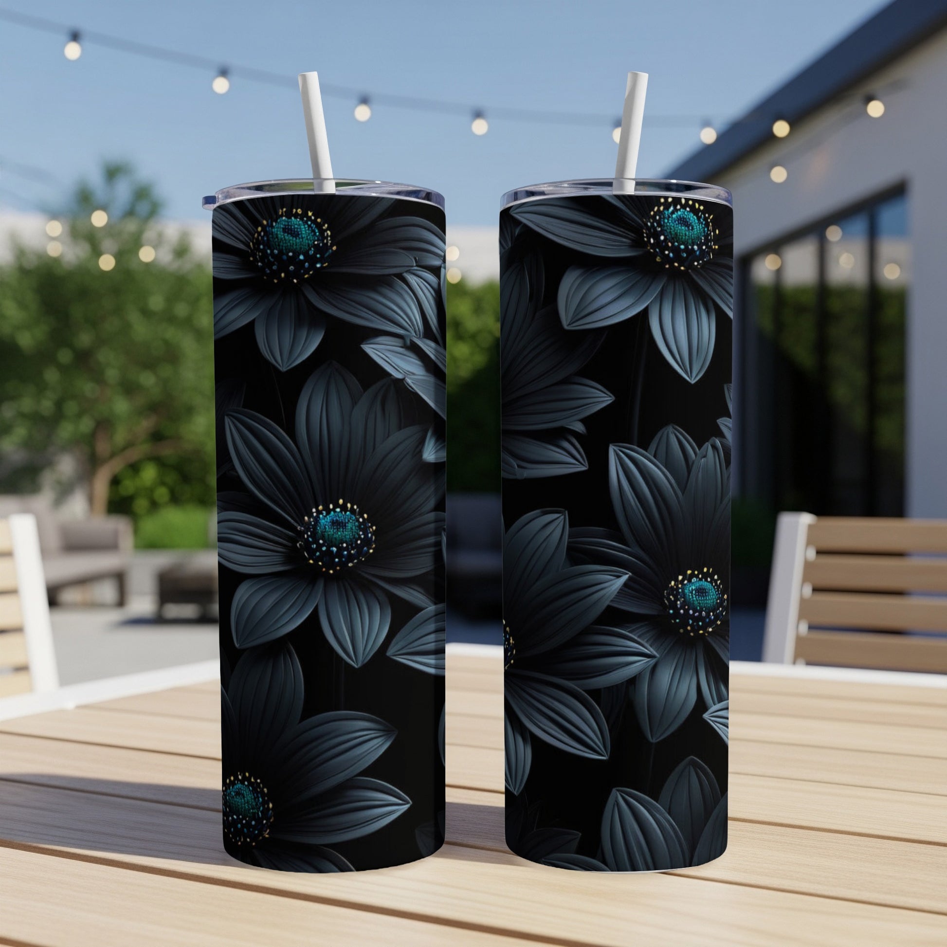 Two black floral tumblers with teal centers stand on a table outdoors.