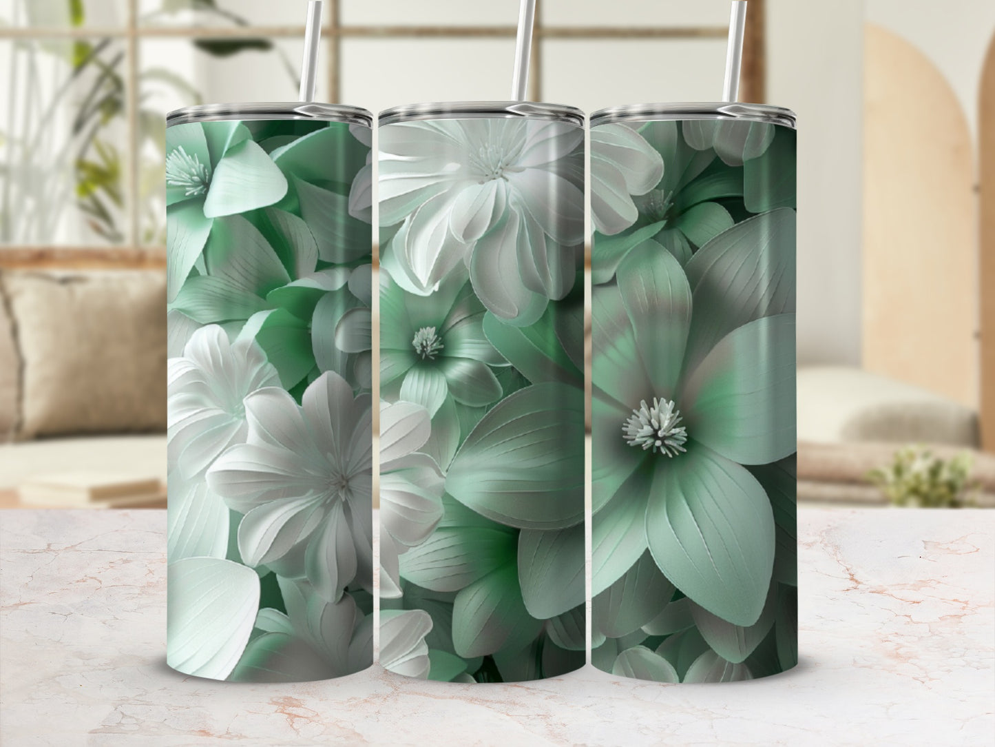 Three mint green floral tumblers with straws on a marble surface.