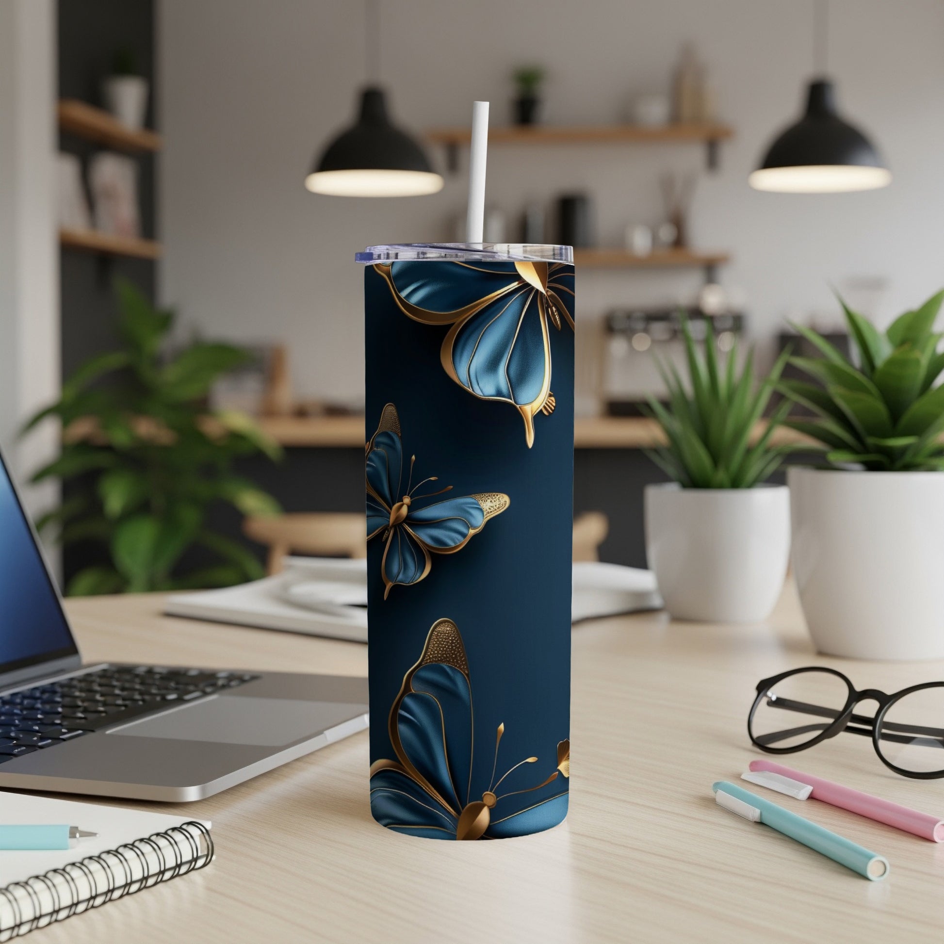 Navy blue tumbler with gold butterflies and a white straw on a desk.