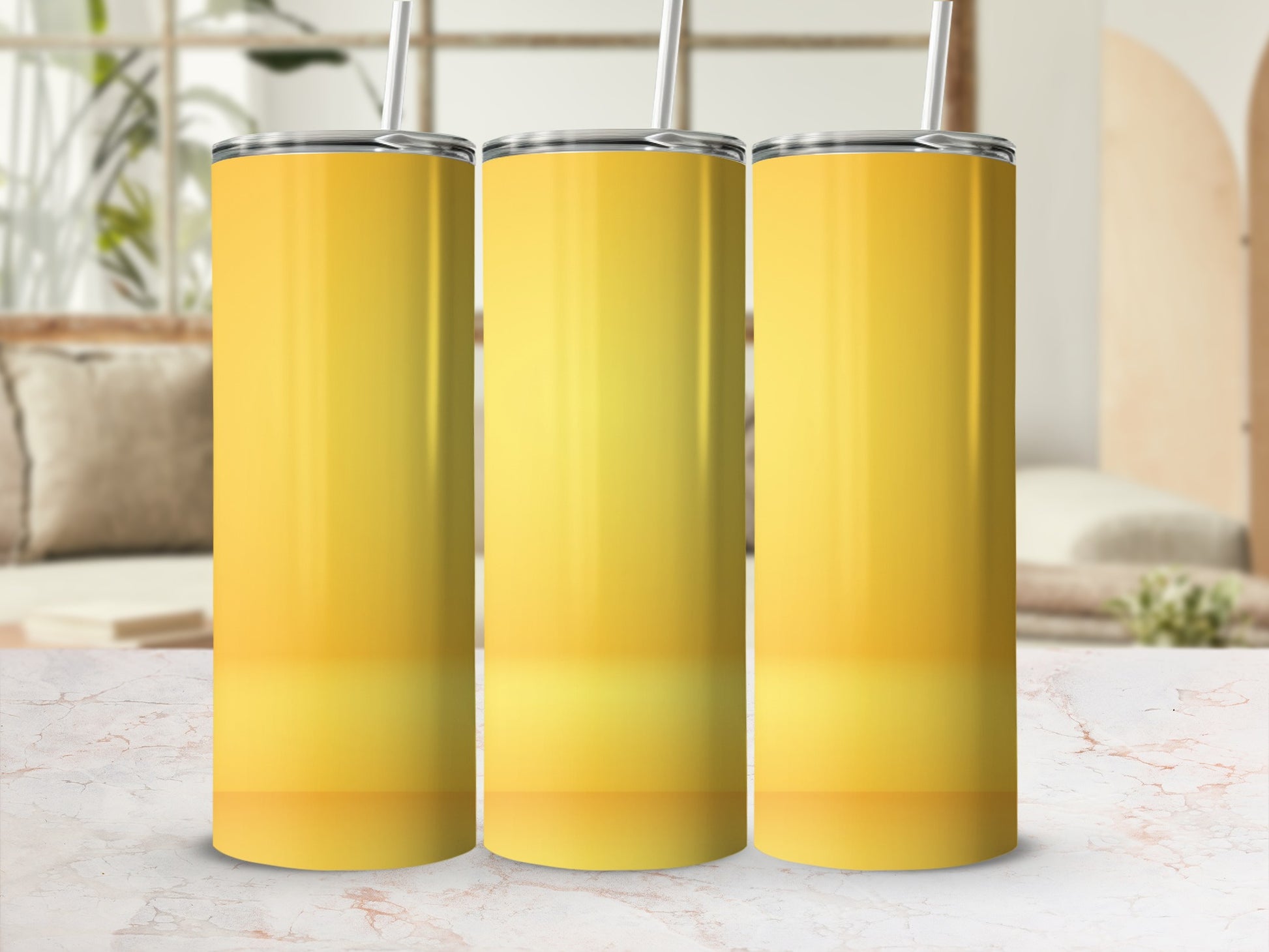 Three yellow gradient tumblers with straws on a marble surface.