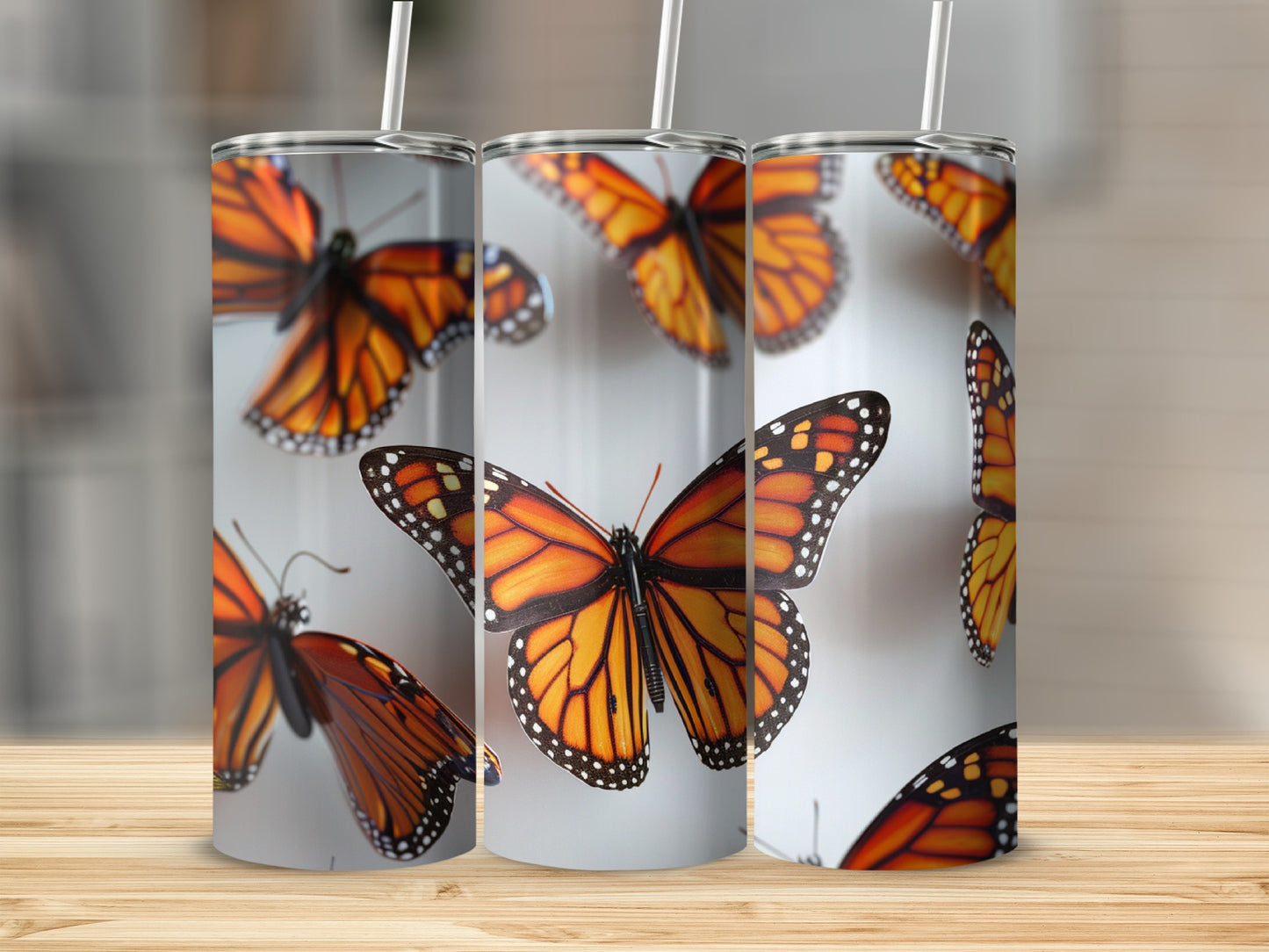 Monarch butterflies on a sublimation tumbler with straws on a wooden surface.