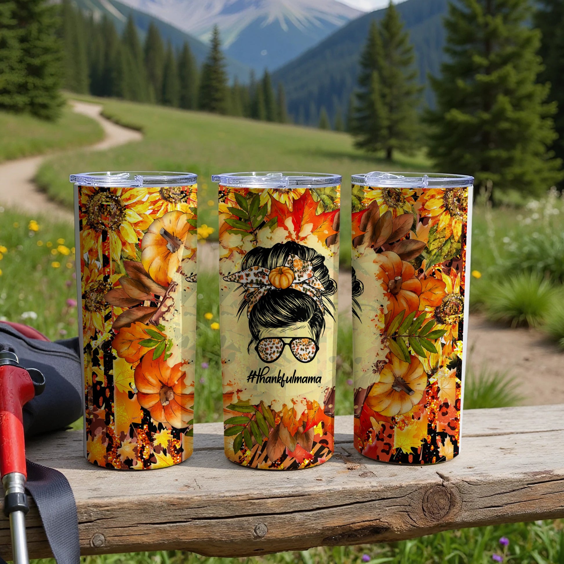 Three tumblers with autumn leaves, pumpkins, and sunflowers displayed outdoors.
