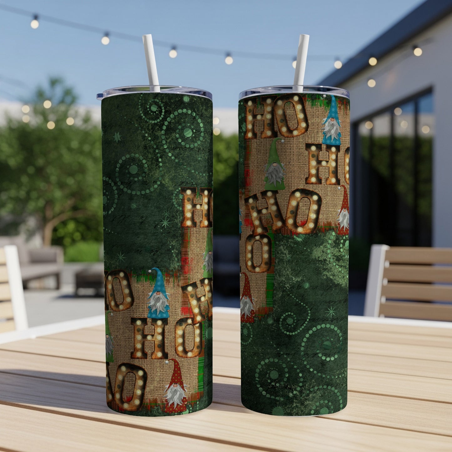 Two green tumblers with "HO HO HO" and gnome designs, on a table.
