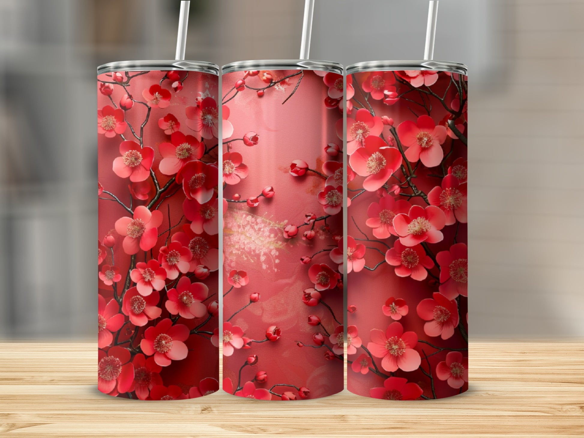 Three tumblers with a red floral design on a wooden surface.