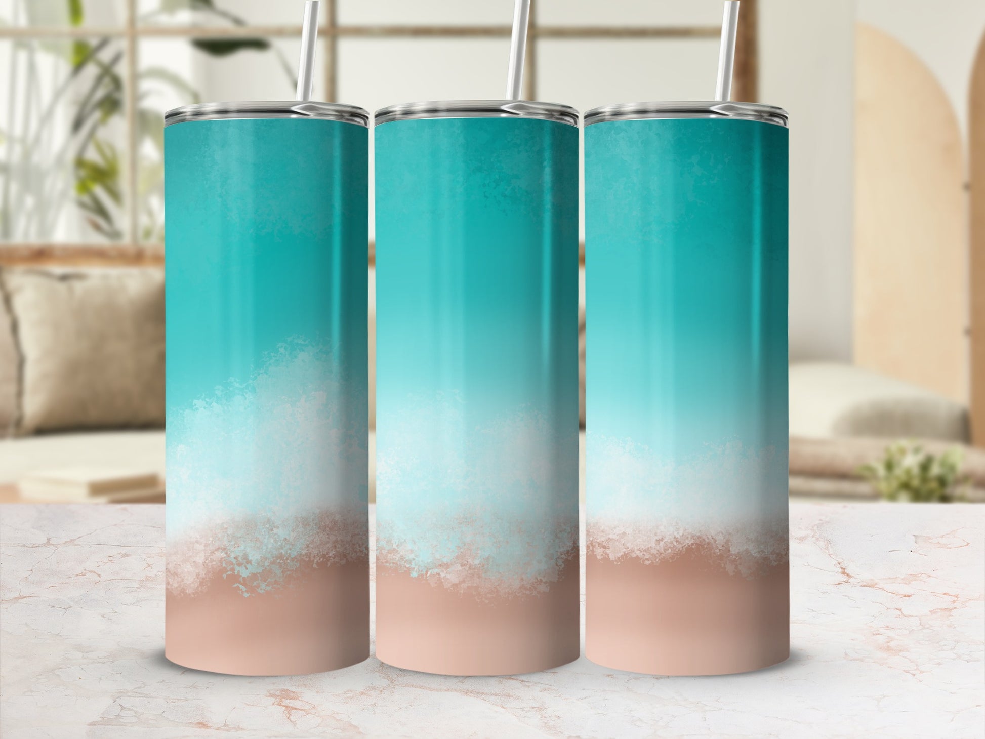 Three teal and sand gradient tumblers with straws on a marble surface.