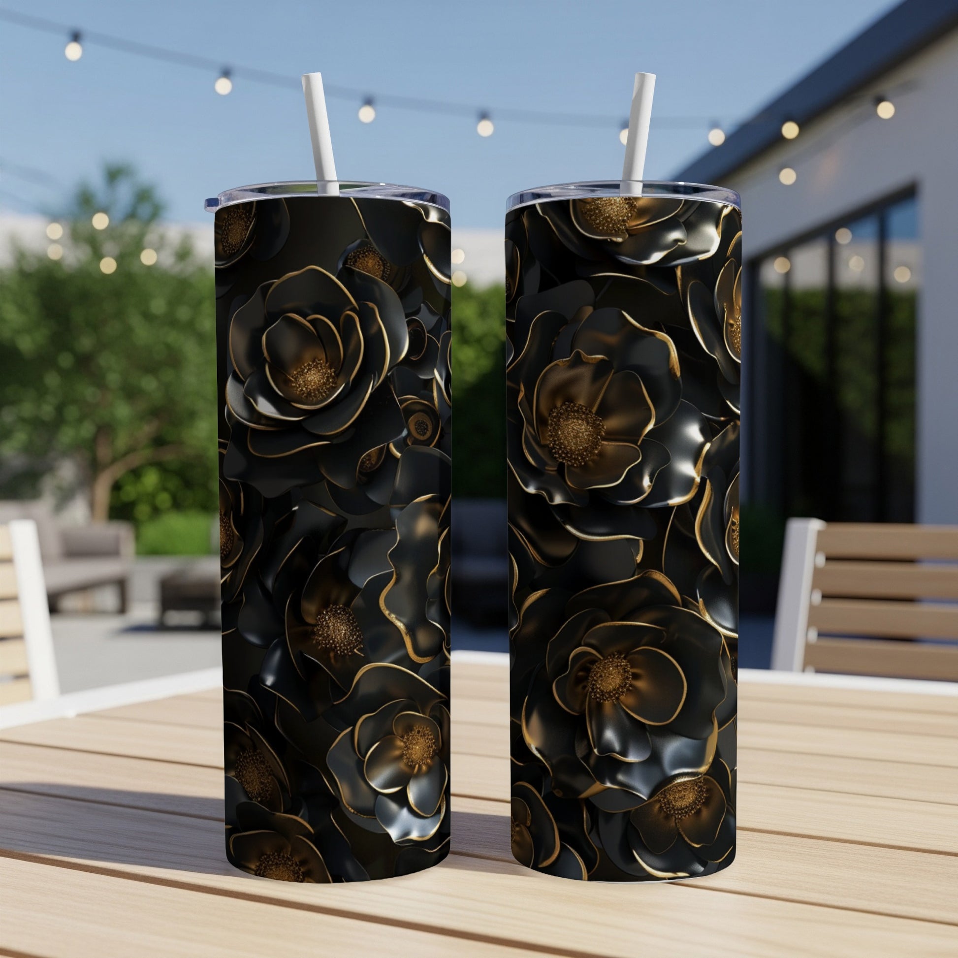 Two black floral tumblers with gold accents on an outdoor table.