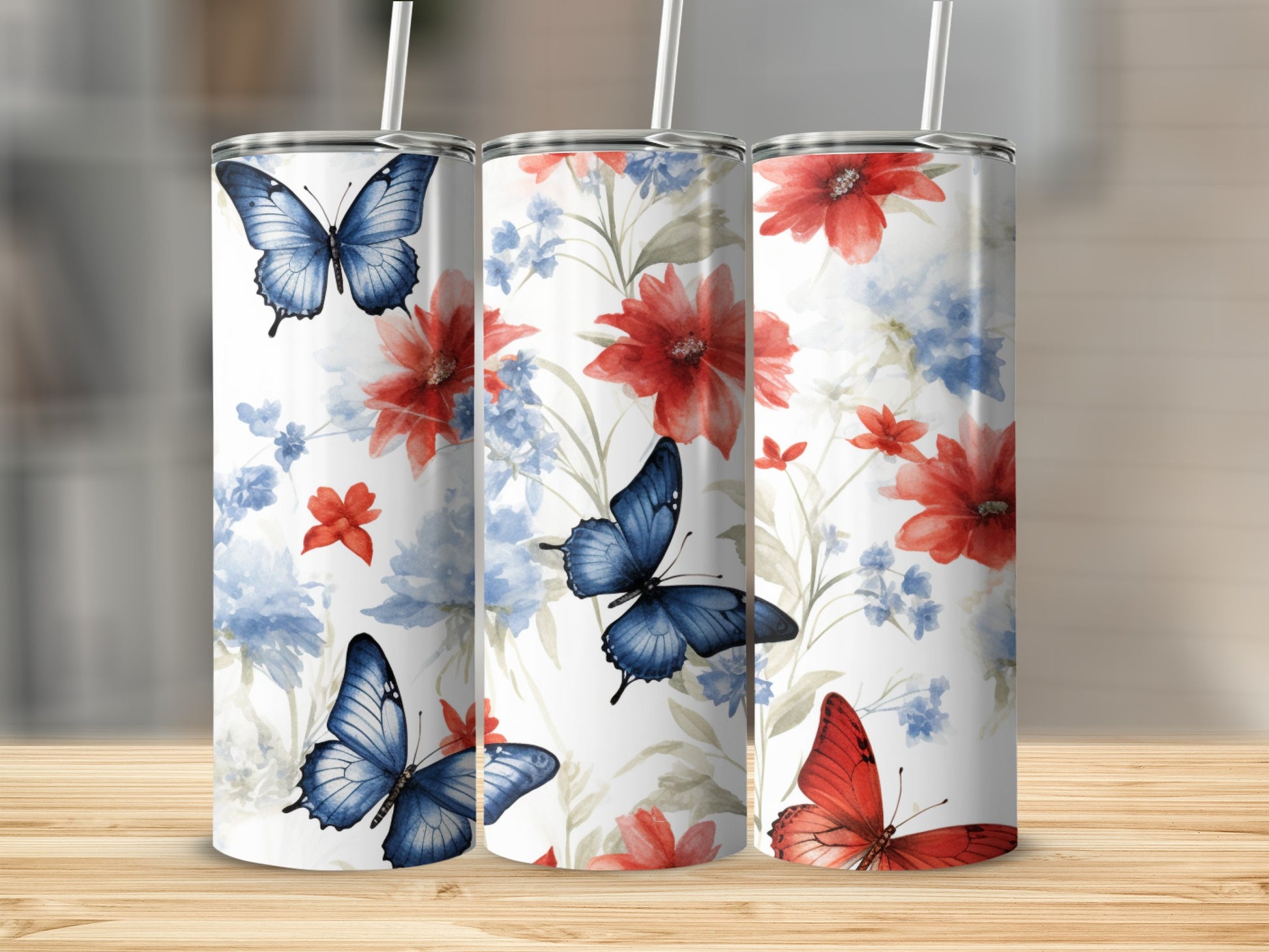 Three tumblers with red flowers and blue butterflies on a wooden surface.