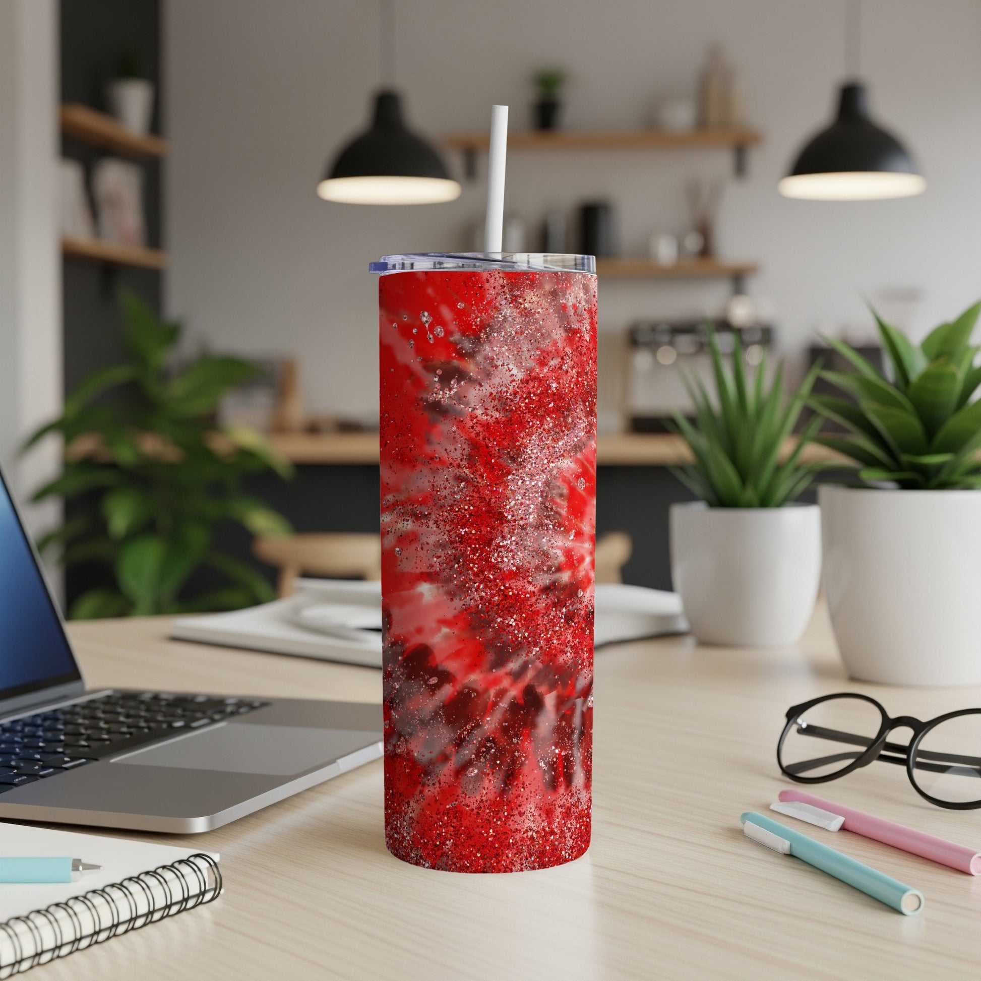 Red glitter abstract pattern tumbler with straw on desk.