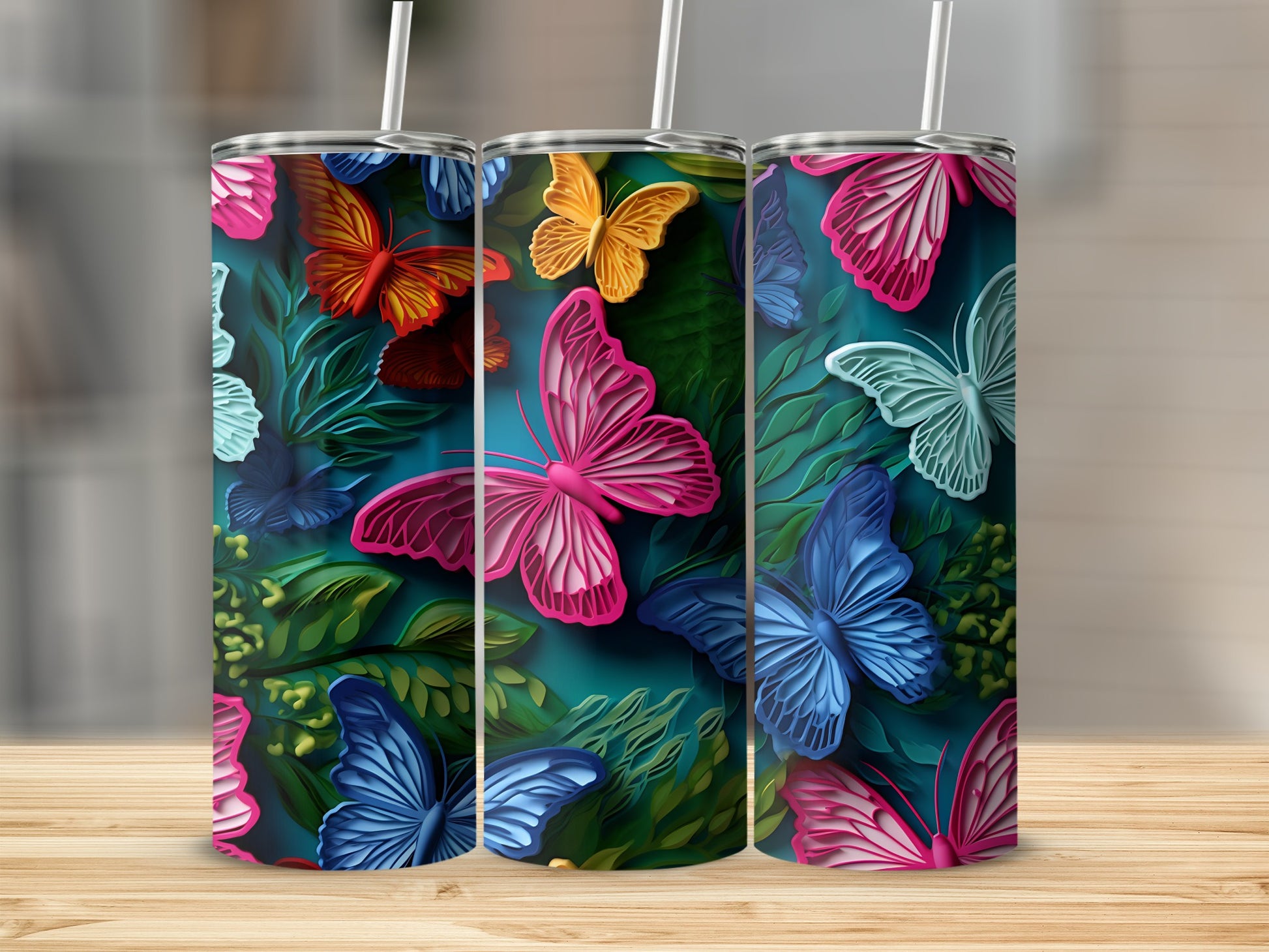 Three tumblers with colorful butterfly designs against a dark, leafy background.
