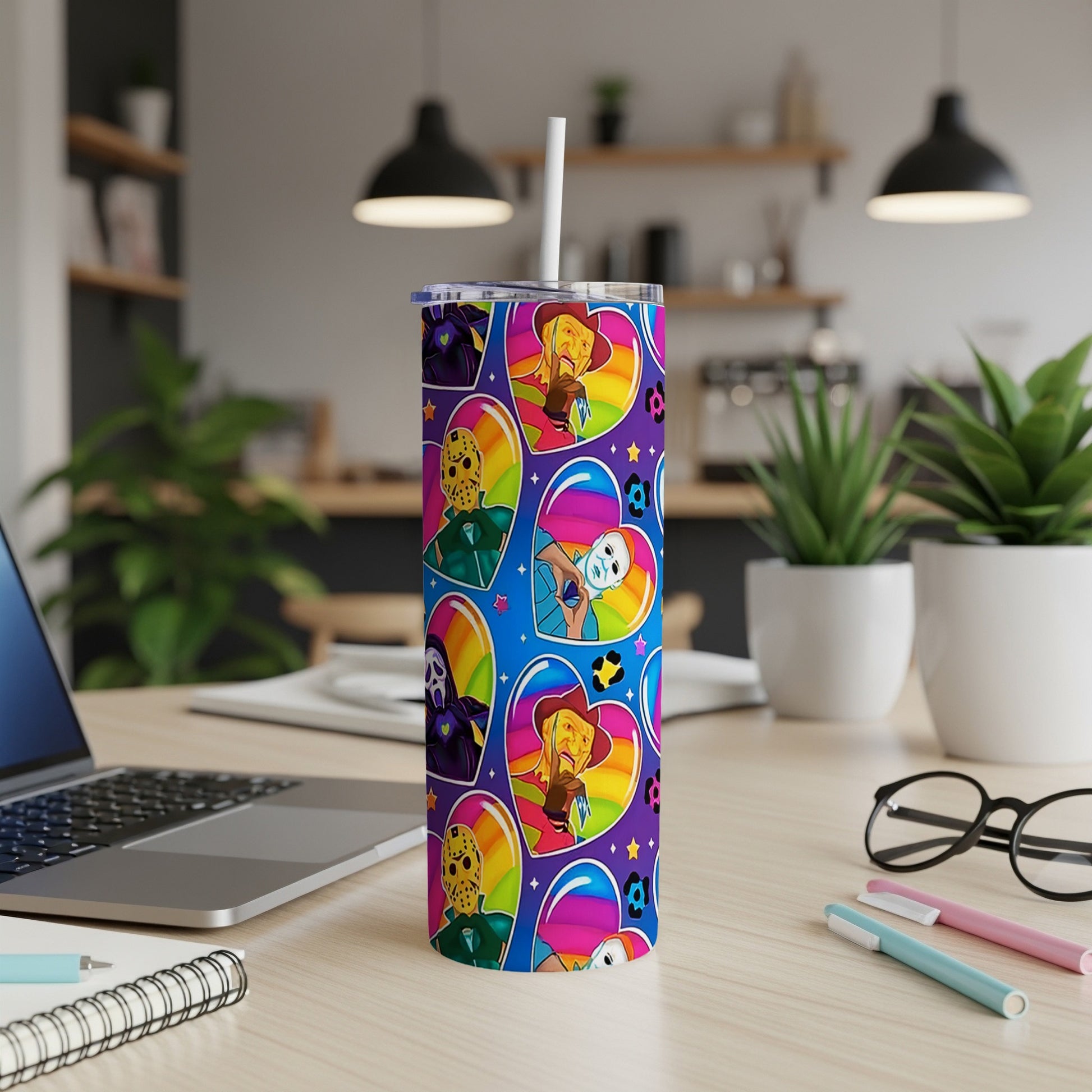 Tumbler with cartoon horror characters and rainbow hearts on a desk.