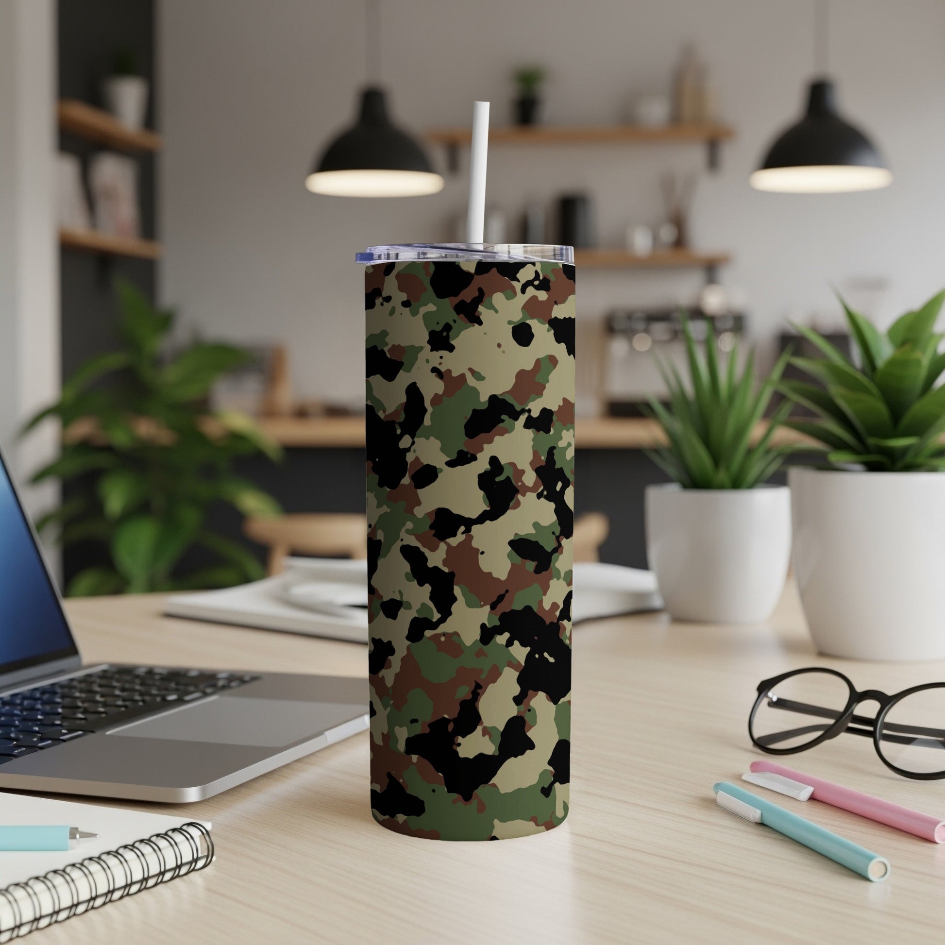 Tumbler with a camouflage pattern and a white straw on a wooden desk.