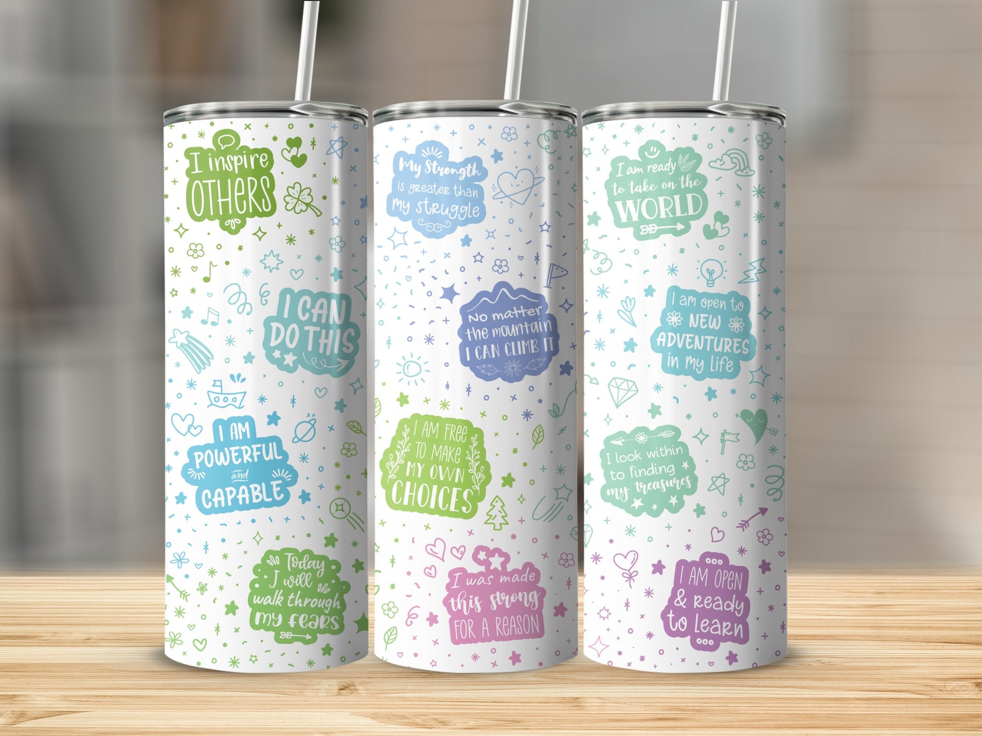 Three tumblers with inspirational quotes and doodles on a wooden surface.