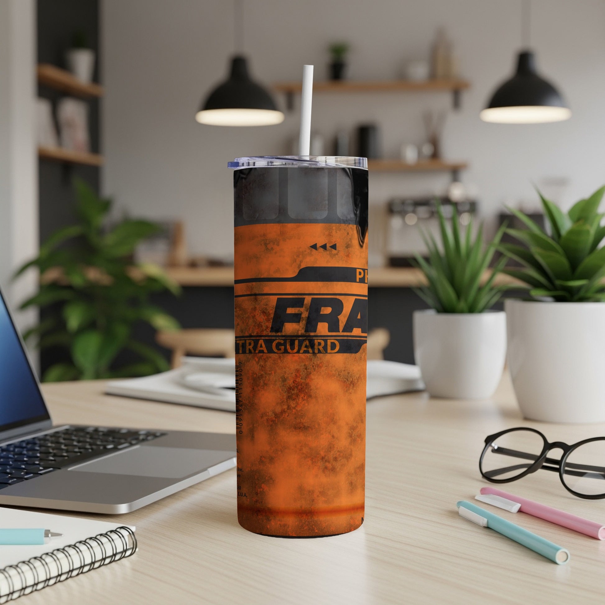 Orange tumbler with "FRAG-GUARD" text on a desk with a laptop.