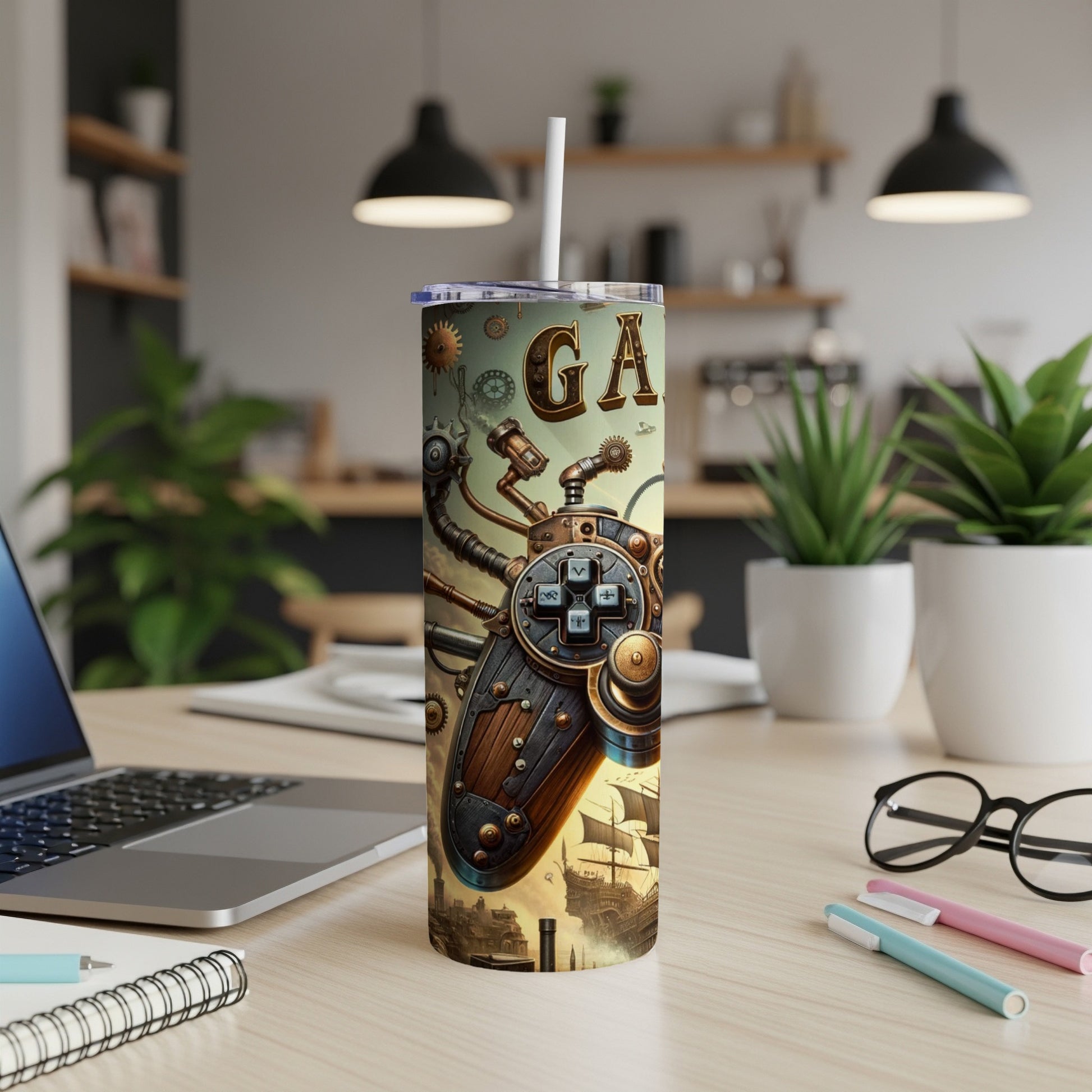 Steampunk gamepad graphic on a tall tumbler with a straw, on a desk.