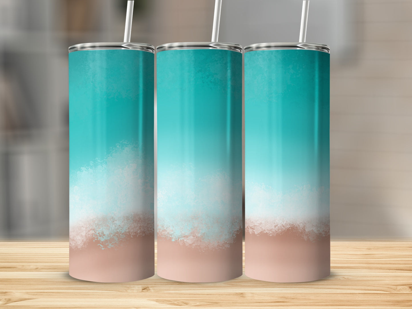 Three teal and sand gradient tumblers with straws on a wooden surface.