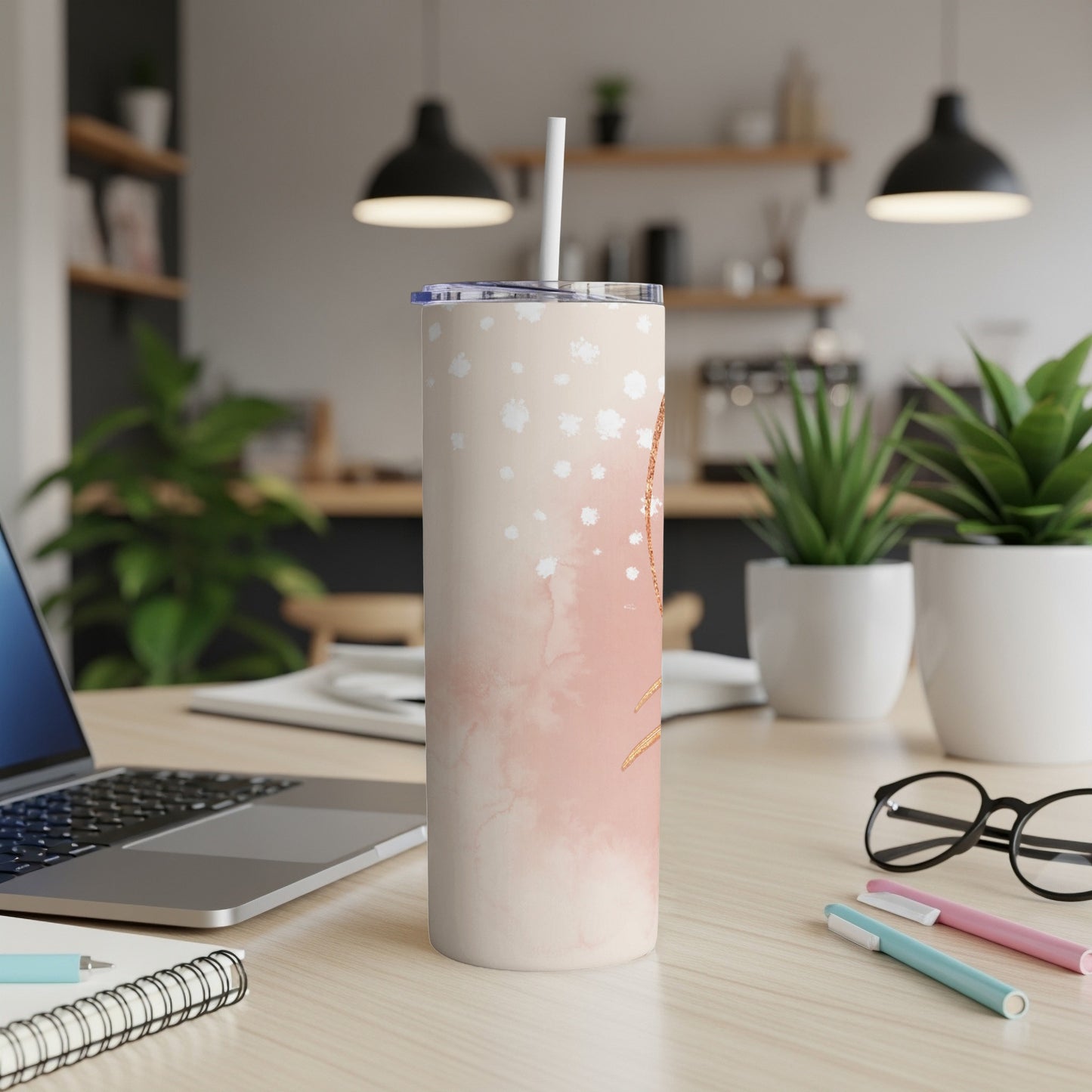 Cream and pink watercolor tumbler with straw on a desk.