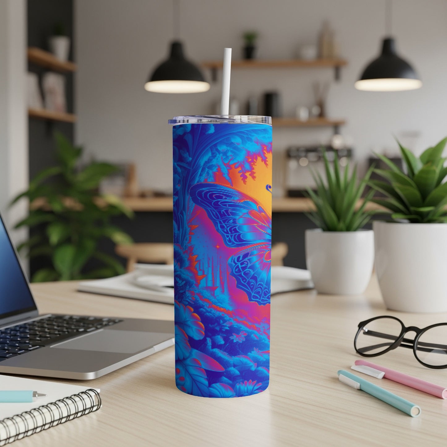 Blue and orange butterfly pattern on a tall tumbler with a straw on a desk.