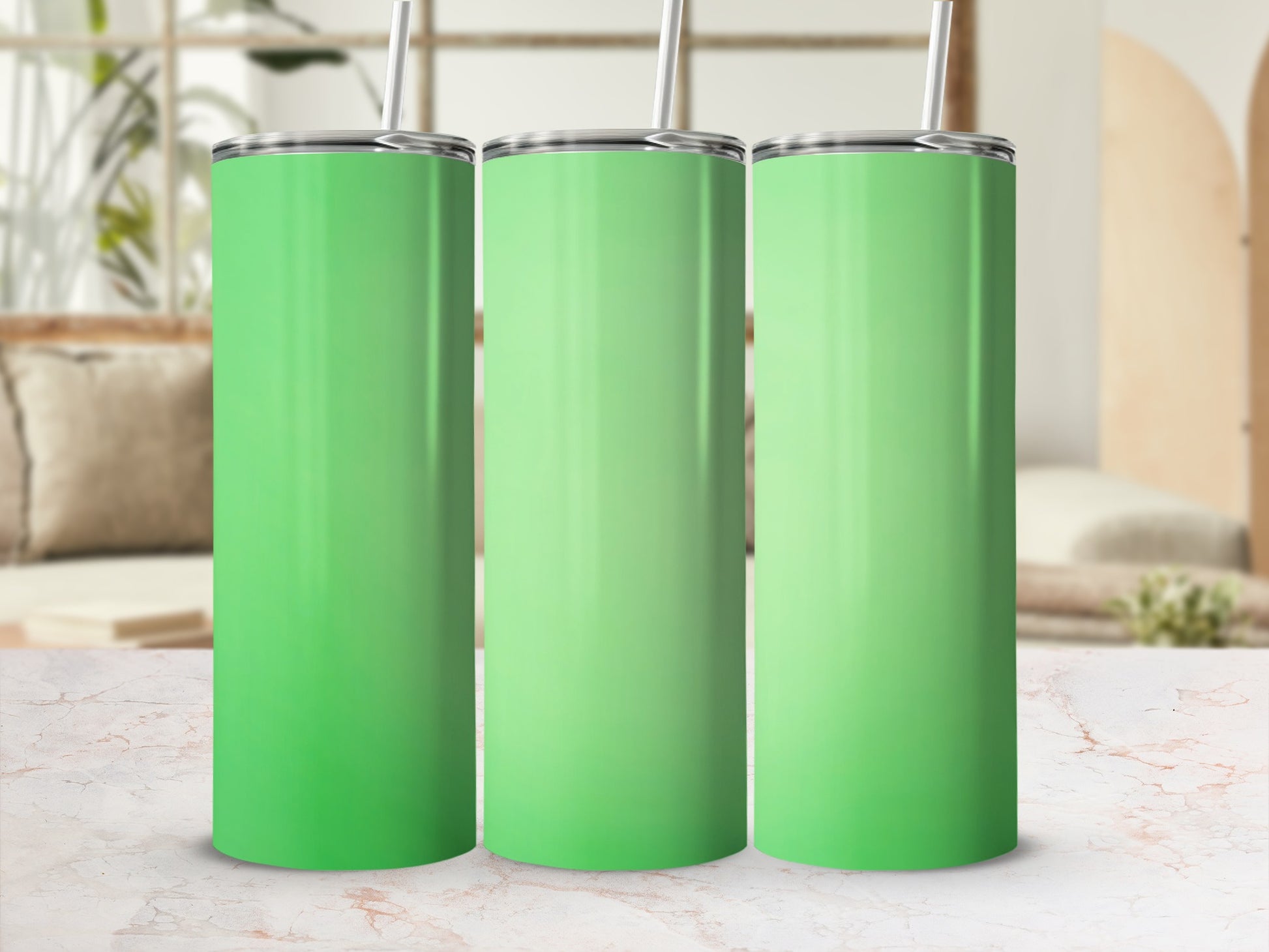 Three plain green tumblers with straws on a marble countertop.