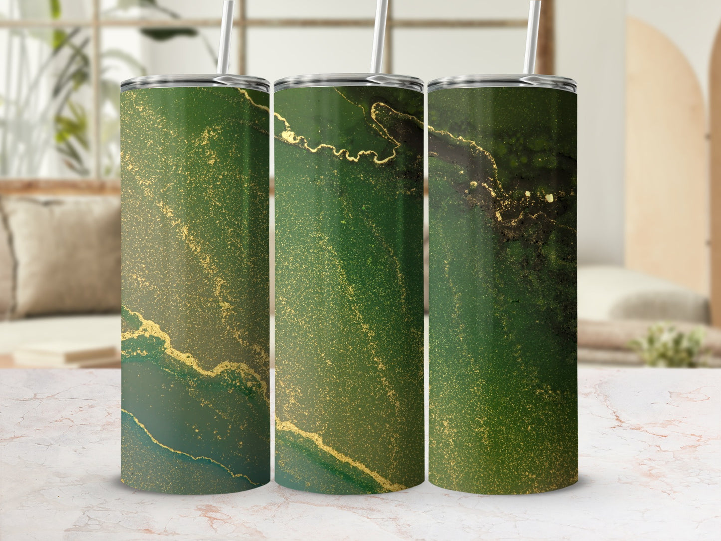 Three green and gold marbled tumblers with straws on a marble surface.