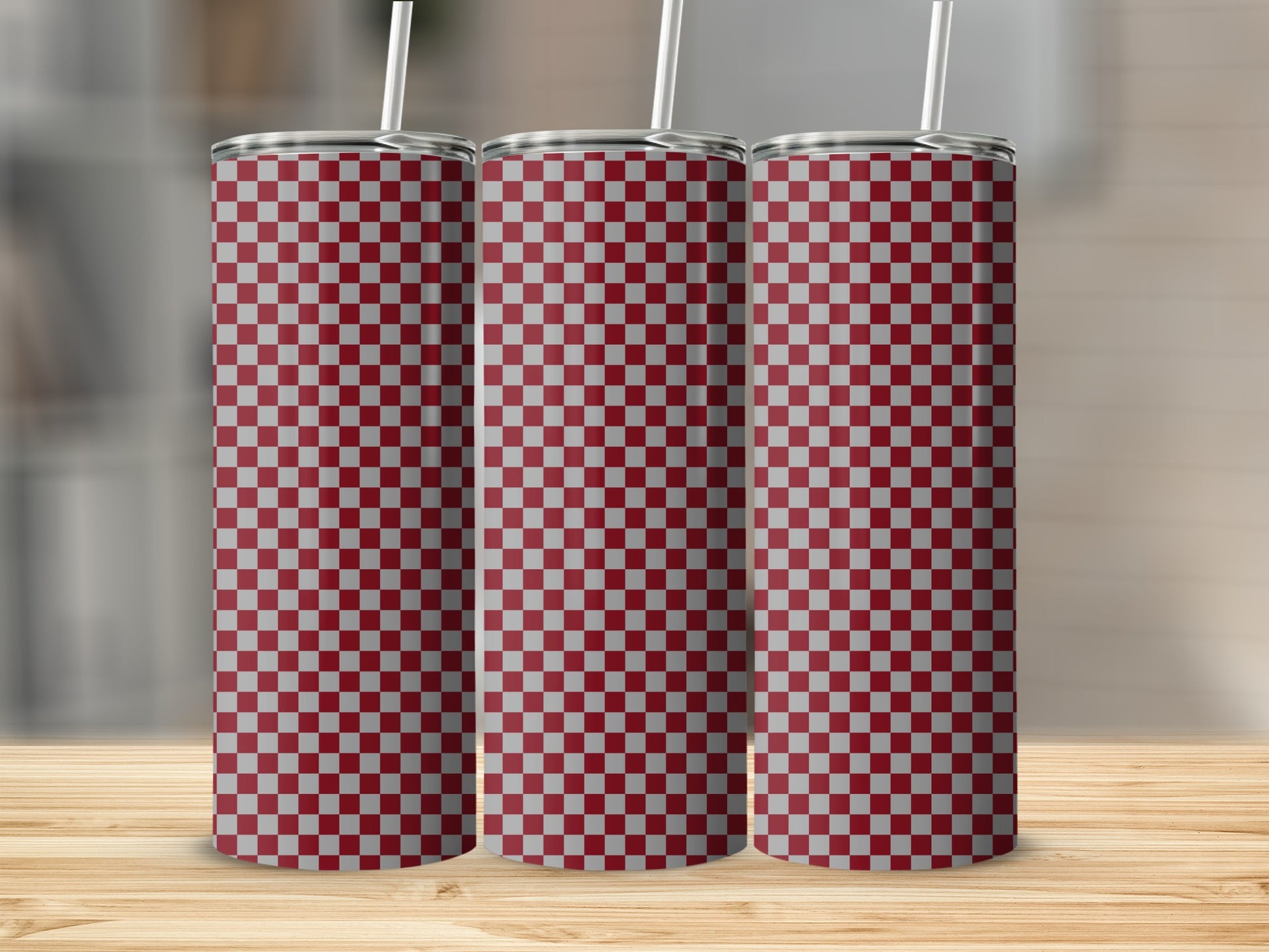 Three red and white checkered tumblers with straws on a wooden surface.