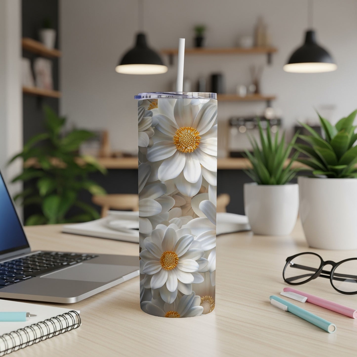 White floral patterned tumbler with straw on a wooden desk.