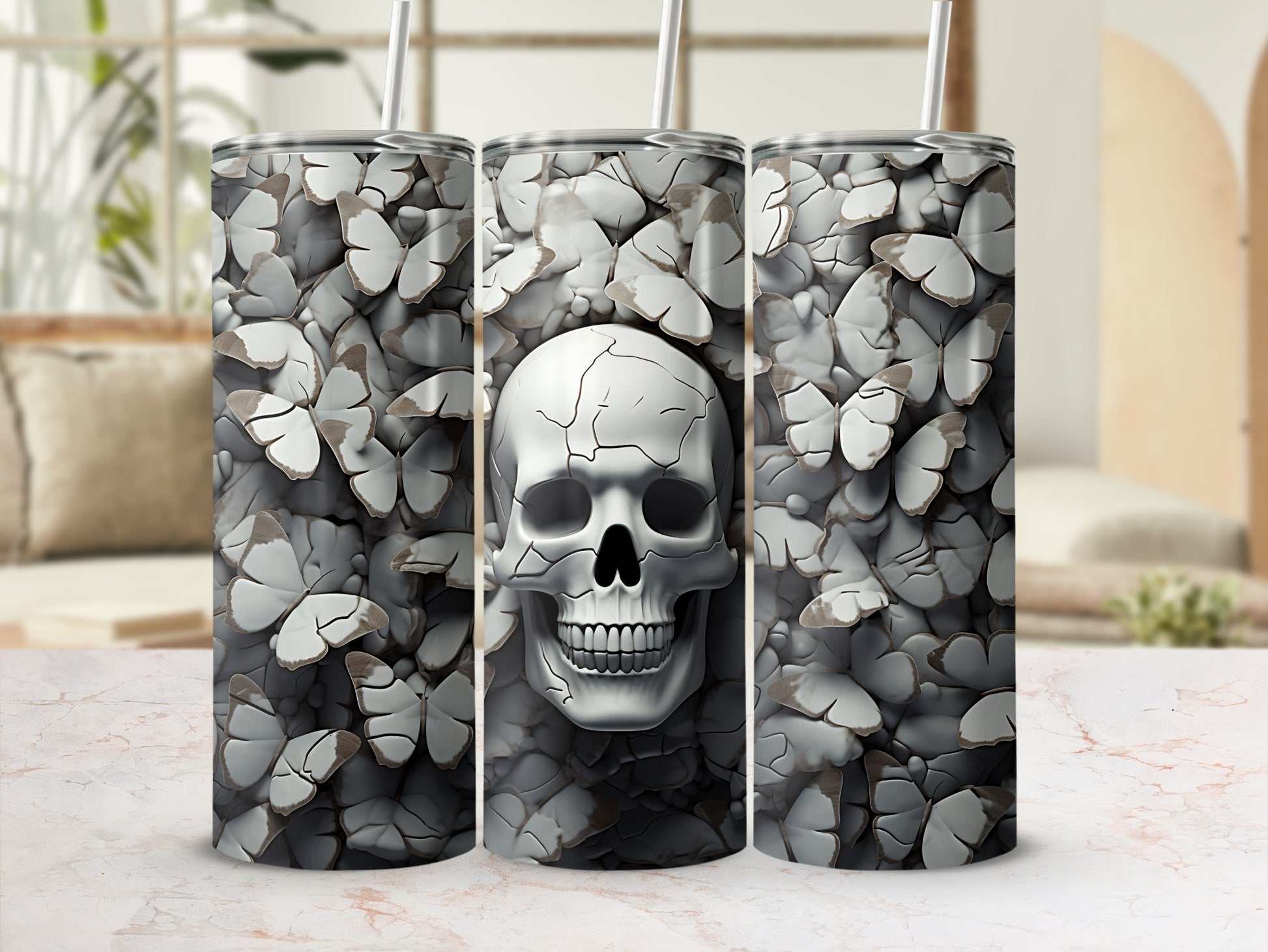 Three tumblers with a cracked skull and butterfly pattern on a marble surface.