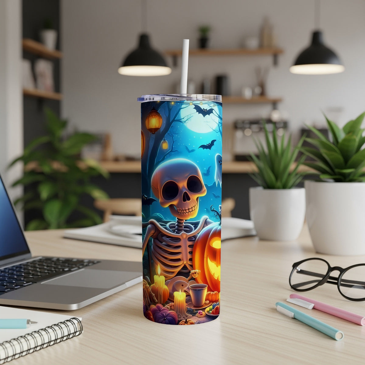 Halloween tumbler with skeleton and jack-o'-lantern on a desk.