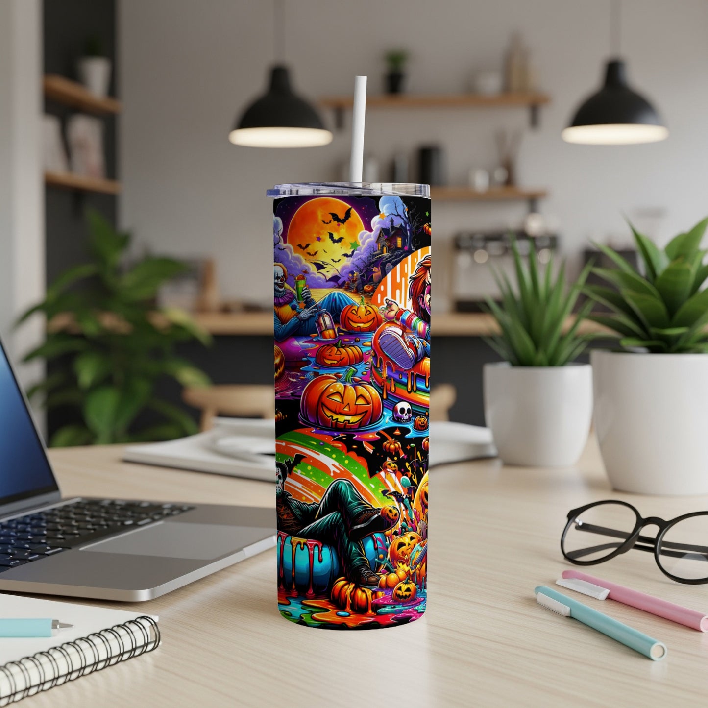 Colorful Halloween tumbler with pumpkins, ghosts, and spooky characters on a desk.