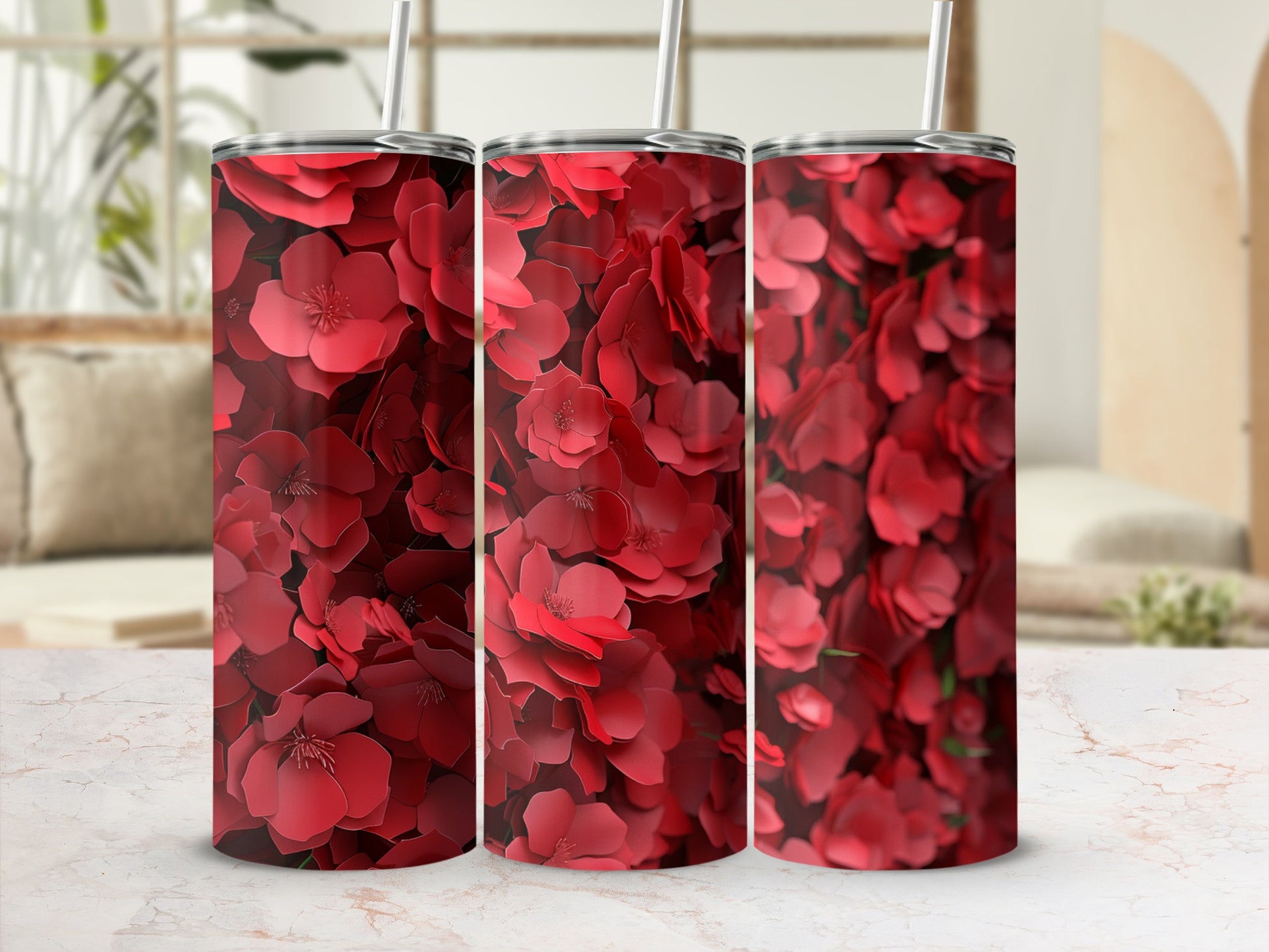 Three red floral tumblers displayed on a marble countertop.