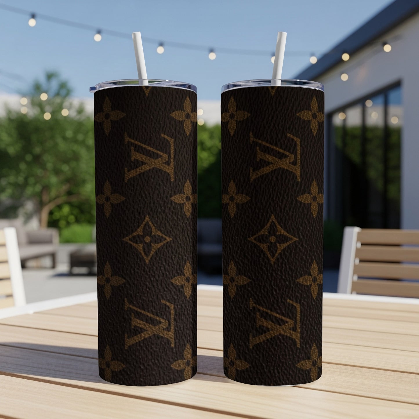 Two tall brown tumblers with repeating LV logo pattern, on outdoor table.