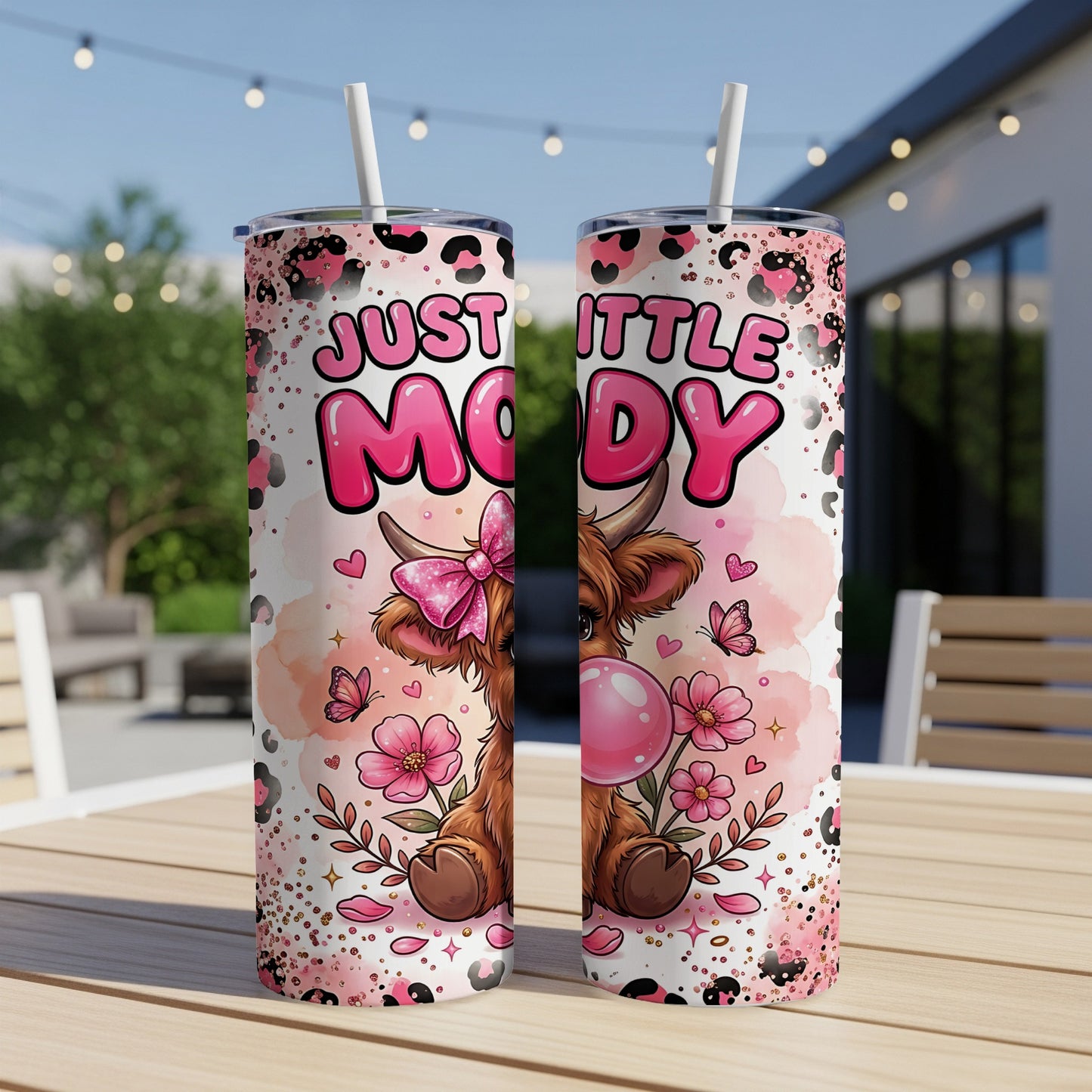 Pink tumbler with "Just a Little Moody" text and a cartoon cow with a bow.