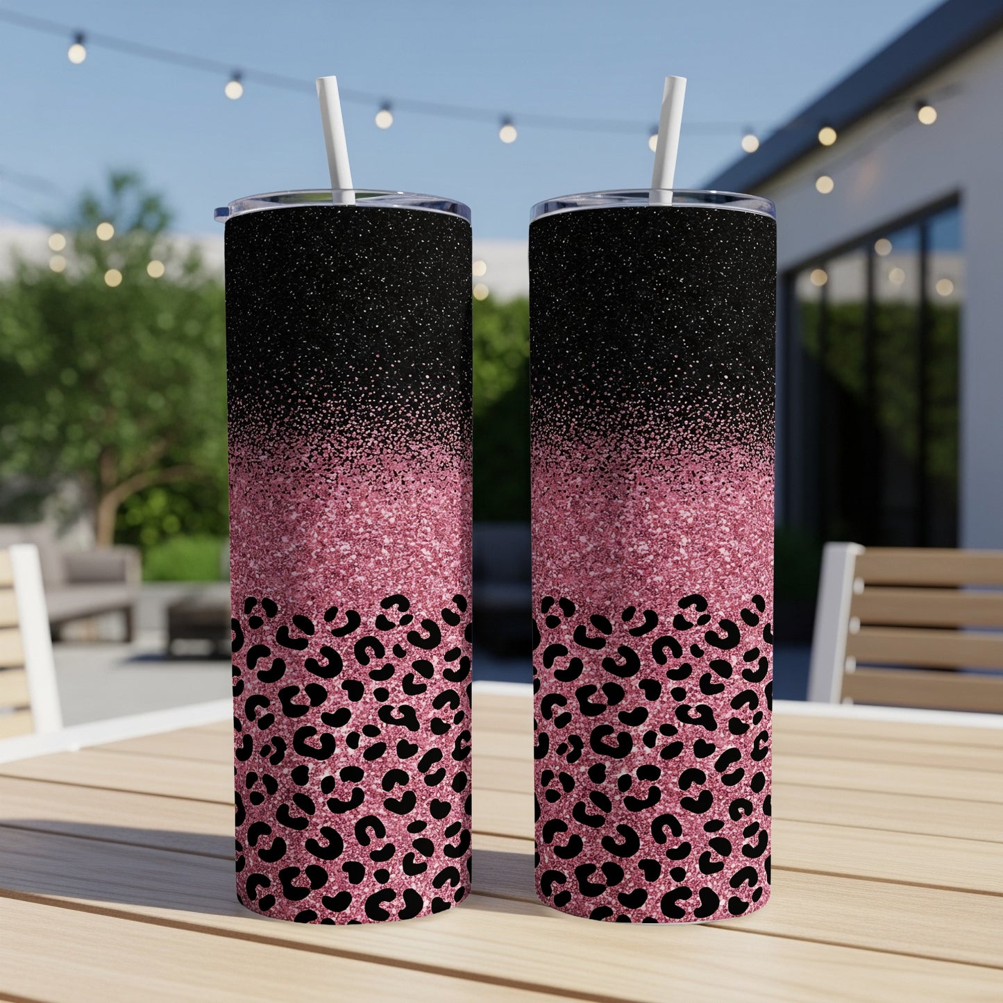 Two glittery tumblers with leopard print design on wooden table outdoors.